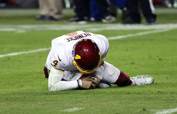 LANDOVER, MARYLAND - JANUARY 09:  Quarterback Taylor Heinicke #4 of the Washington Football Team grabs lies on the ground injured during the 4th quarter of the game against the Tampa Bay Buccaneers at FedExField on January 09, 2021 in Landover, Maryland. (Photo by Patrick Smith/Getty Images)