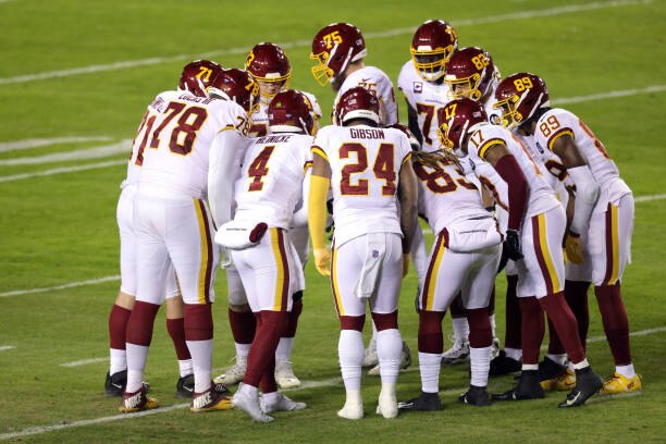 LANDOVER, MARYLAND - JANUARY 09: Quarterback Taylor Heinicke #4 of the Washington Football Team huddles with the team during the first half of the NFC Wild Card playoff game against the Tampa Bay Buccaneers at FedExField on January 09, 2021 in Landover, Maryland. (Photo by Rob Carr/Getty Images)