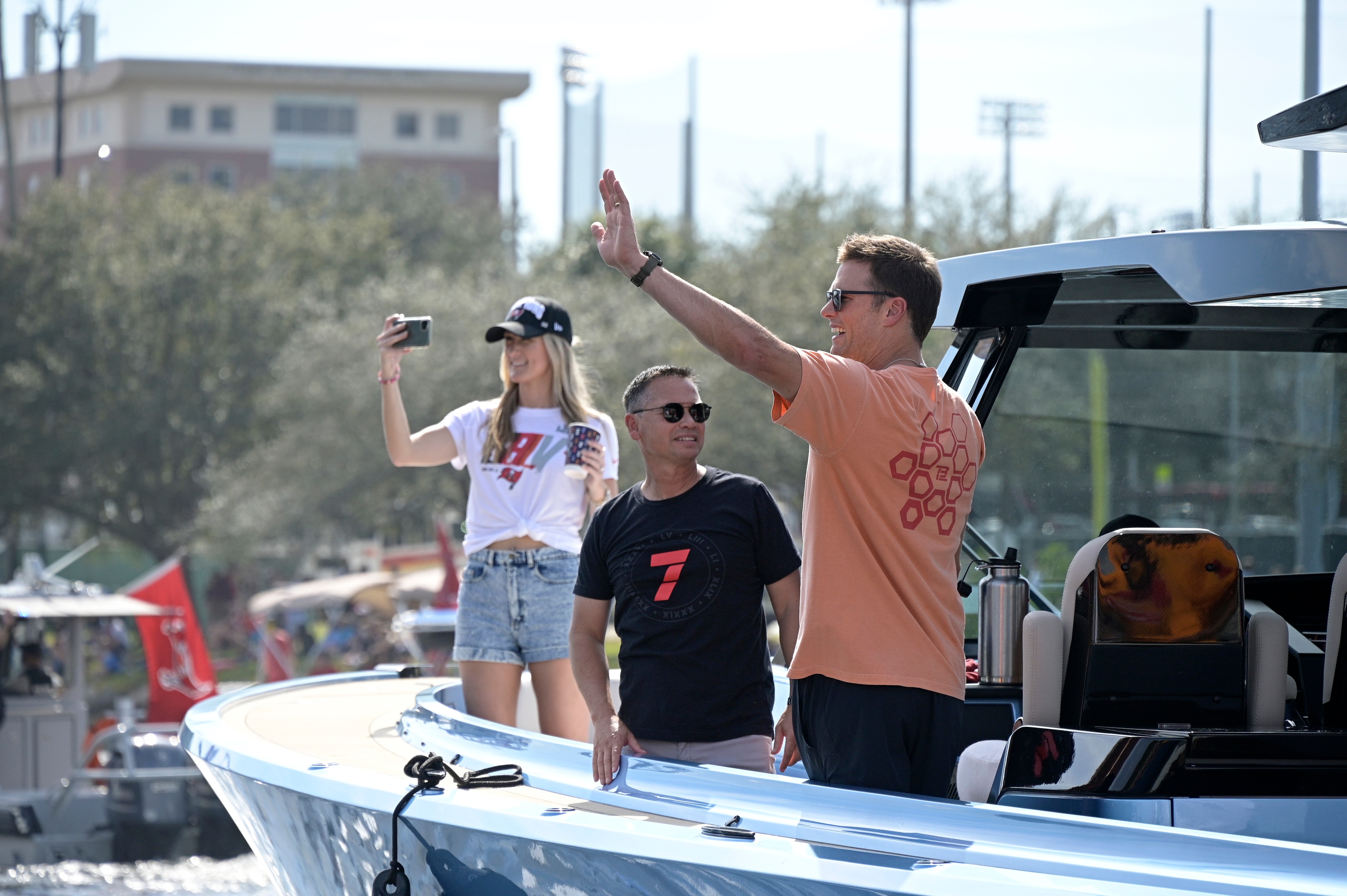 Tampa Bay Buccaneers quarterback Tom Brady waves to fans as his personal trainer Alex Guerrero, left, watches during a celebration of their Super Bowl 55 victory over the Kansas City Chiefs with a boat parade, Wednesday, Feb. 10, 2021, in Tampa, Fla. (AP Photo/Phelan M. Ebenhack)