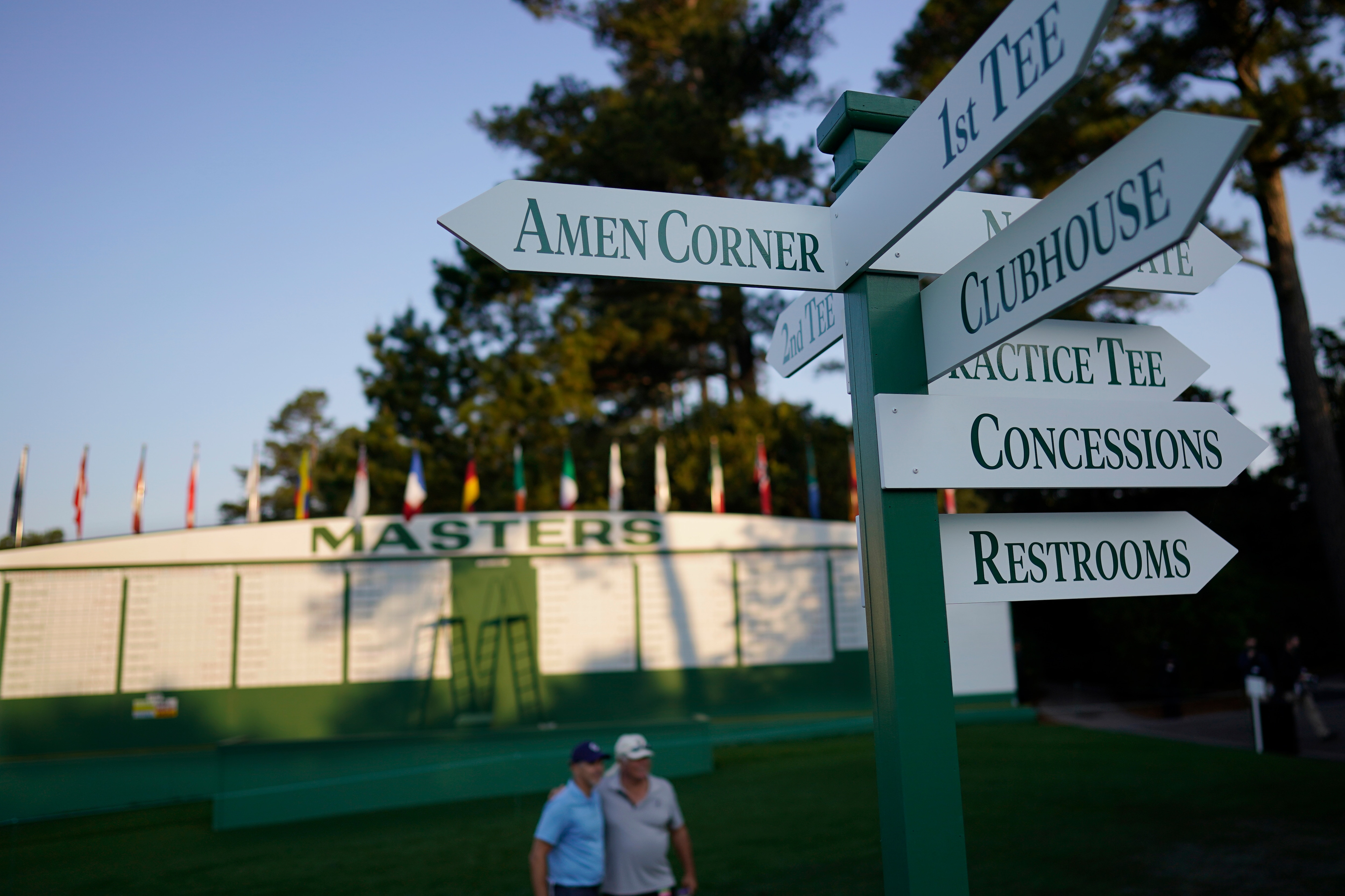 Spectators pose for a photo at the entrance to Augusta National Golf Course before a practice round for the Masters golf tournament on Wednesday, April 7, 2021, in Augusta, Ga. (AP Photo/David J. Phillip)