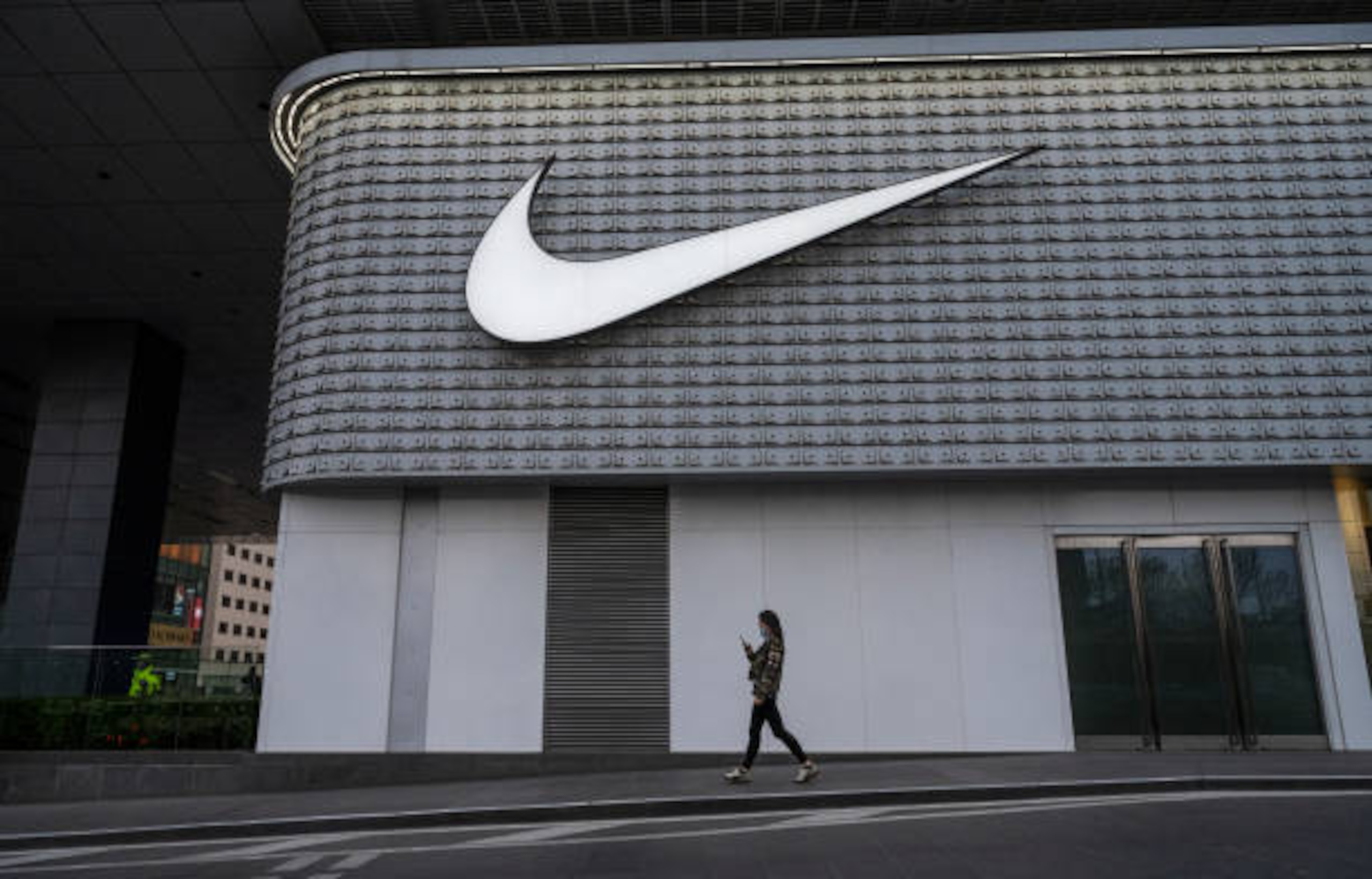 BEIJING, CHINA - APRIL 08: A woman walks outside a Nike store at a shopping area on April 8, 2021 in Beijing, China. (Photo by Kevin Frayer/Getty Images)