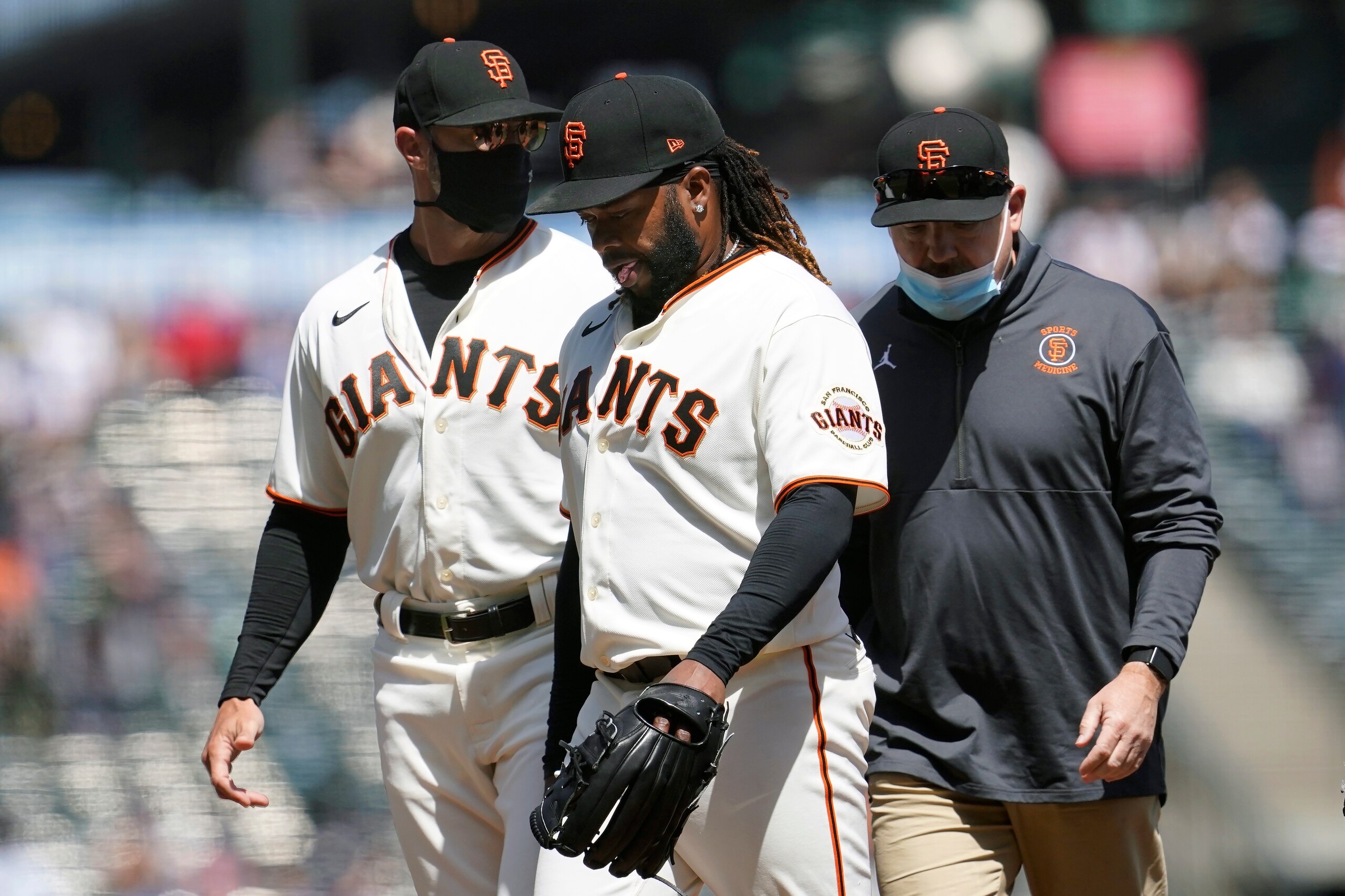 San Francisco Giants starting pitcher Johnny Cueto, middle, walks toward the dugout next to manager Gabe Kapler, left, as he leaves the game during the sixth inning of a baseball game against the Cincinnati Reds in San Francisco, Wednesday, April 14, 2021. (AP Photo/Jeff Chiu)