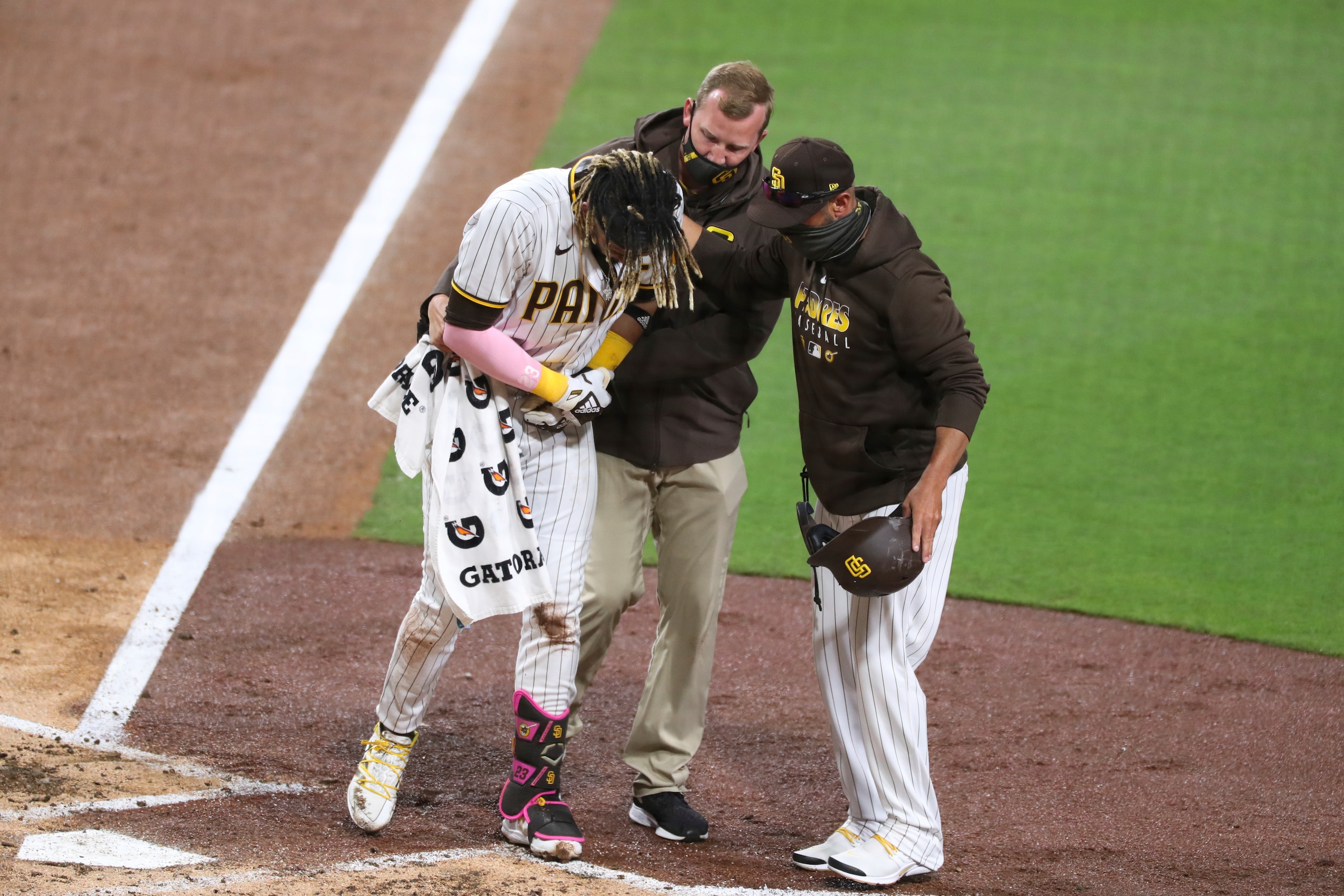 San Diego Padres manger Jayce Tingler, right, and a trainer, center, help Fernando Tatis Jr., left, off the field after Tatis hurt his shoulder while swinging at a pitch in the third inning of a baseball game against the San Francisco Giants, Monday, April 5, 2021, in San Diego. (AP Photo/Derrick Tuskan) San Diego Padres manger Jayce Tingler, right, and a trainer, center, help Fernando Tatis Jr., left, off the field after Tatis hurt his shoulder while swinging at a pitch in the third inning of a baseball game against the San Francisco Giants, Monday, April 5, 2021, in San Diego. (AP Photo/Derrick Tuskan)