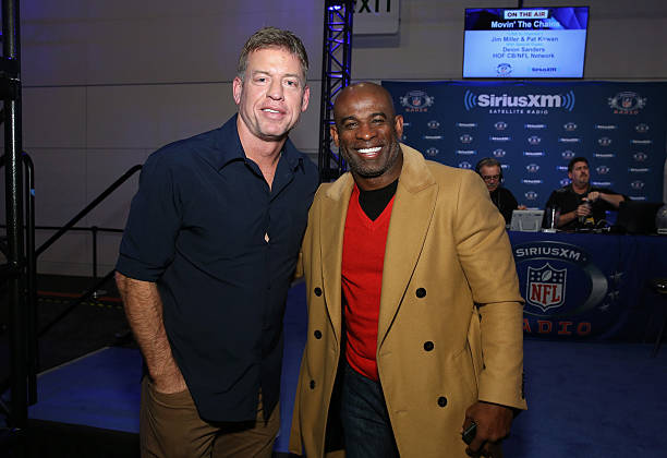 SAN FRANCISCO, CA - FEBRUARY 04:  Former NFL players with the Dallas Cowboys Troy Aikman (L) and Deion Sanders visit the SiriusXM set at Super Bowl 50 Radio Row at the Moscone Center on February 4, 2016 in San Francisco, California.  (Photo by Cindy Ord/Getty Images for SiriusXM)