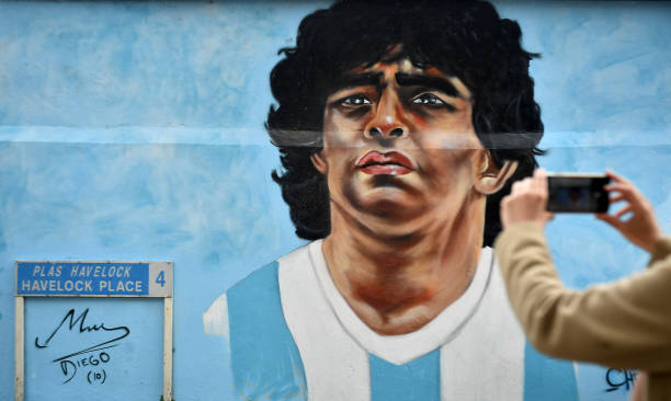 Dublin , Ireland - 12 April 2021; A passer-by takes a photo of a mural by Dublin artist Chelsea Jacobs depicting the late Argentine footballer Diego Maradona at Havelock Square in Dublin. (Photo By David Fitzgerald/Sportsfile via Getty Images)
