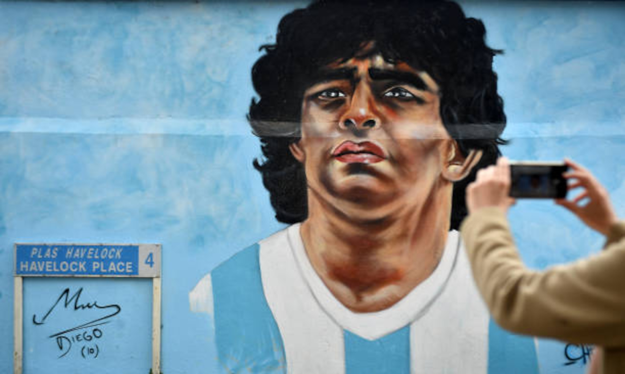 Dublin , Ireland - 12 April 2021; A passer-by takes a photo of a mural by Dublin artist Chelsea Jacobs depicting the late Argentine footballer Diego Maradona at Havelock Square in Dublin. (Photo By David Fitzgerald/Sportsfile via Getty Images)