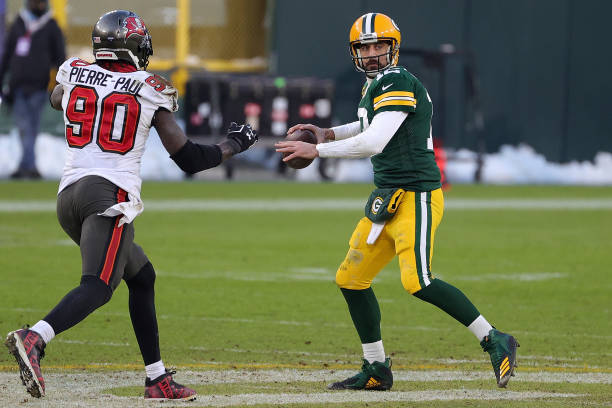 GREEN BAY, WISCONSIN - JANUARY 24: Aaron Rodgers #12 of the Green Bay Packers is pursued by Jason Pierre-Paul #90 of the Tampa Bay Buccaneers during the NFC Championship game at Lambeau Field on January 24, 2021 in Green Bay, Wisconsin. The Buccaneers defeated the Packers 31-26.  (Photo by Stacy Revere/Getty Images)