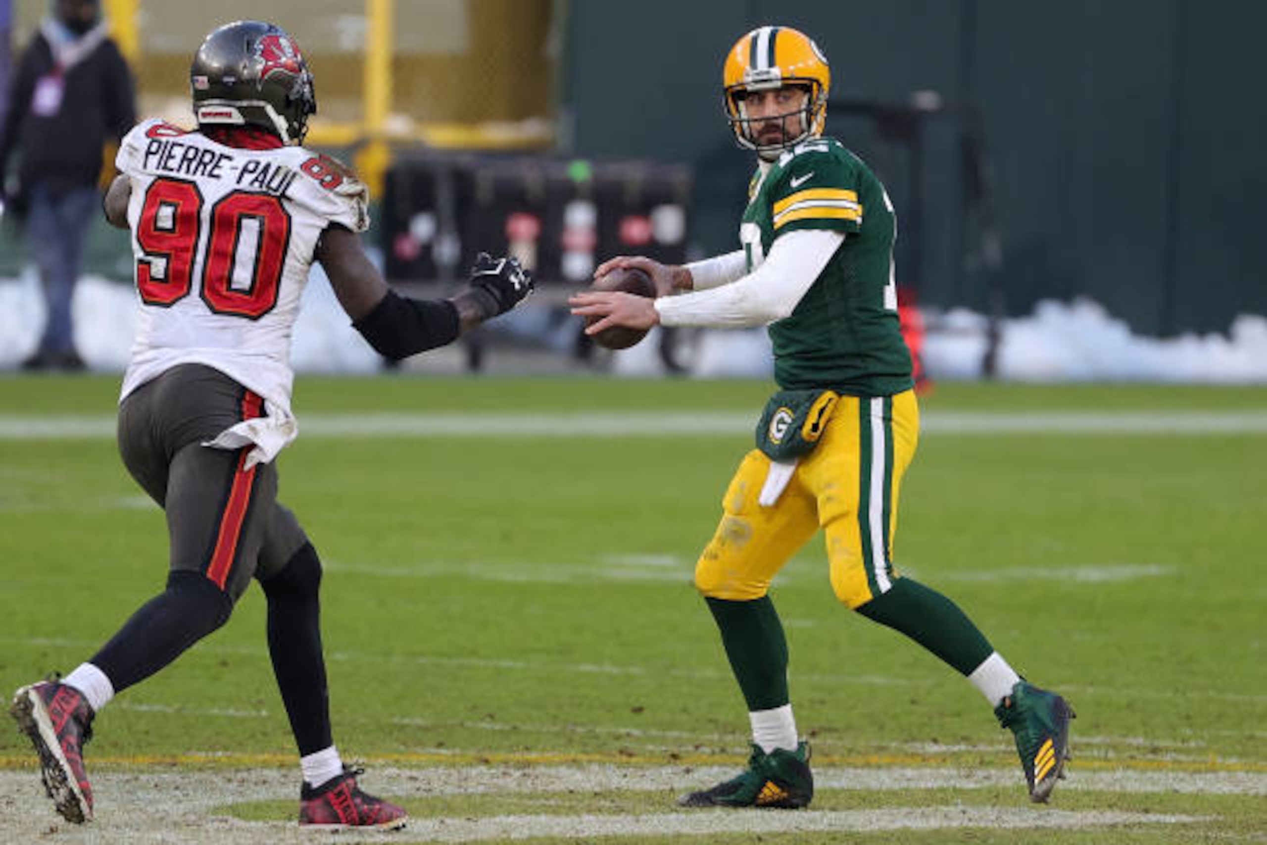GREEN BAY, WISCONSIN - JANUARY 24: Aaron Rodgers #12 of the Green Bay Packers is pursued by Jason Pierre-Paul #90 of the Tampa Bay Buccaneers during the NFC Championship game at Lambeau Field on January 24, 2021 in Green Bay, Wisconsin. The Buccaneers defeated the Packers 31-26.  (Photo by Stacy Revere/Getty Images)