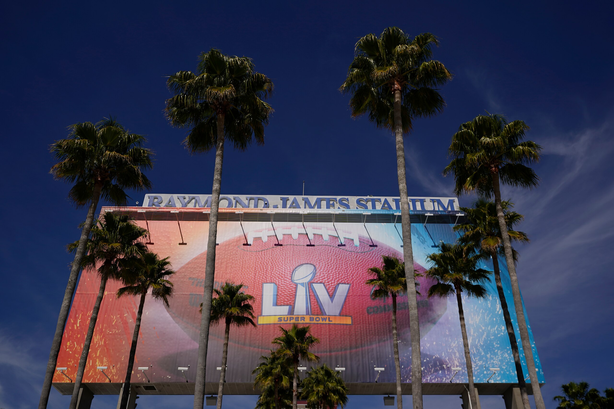 FILE - In this Feb. 4, 2021 file photo A sign for Super Bowl 55 is framed by palm trees at Raymond James Stadium in Tampa, Fla.  Despite the Super Bowl, New Jersey’s casinos and racetracks took in $200 million less in sports bets in February than they did a month earlier. Figures released Tuesday, March 16,  by state regulators show the gambling outlets handled nearly $743 million worth of sports bets in February.  (AP Photo/Charlie Riedel, File)