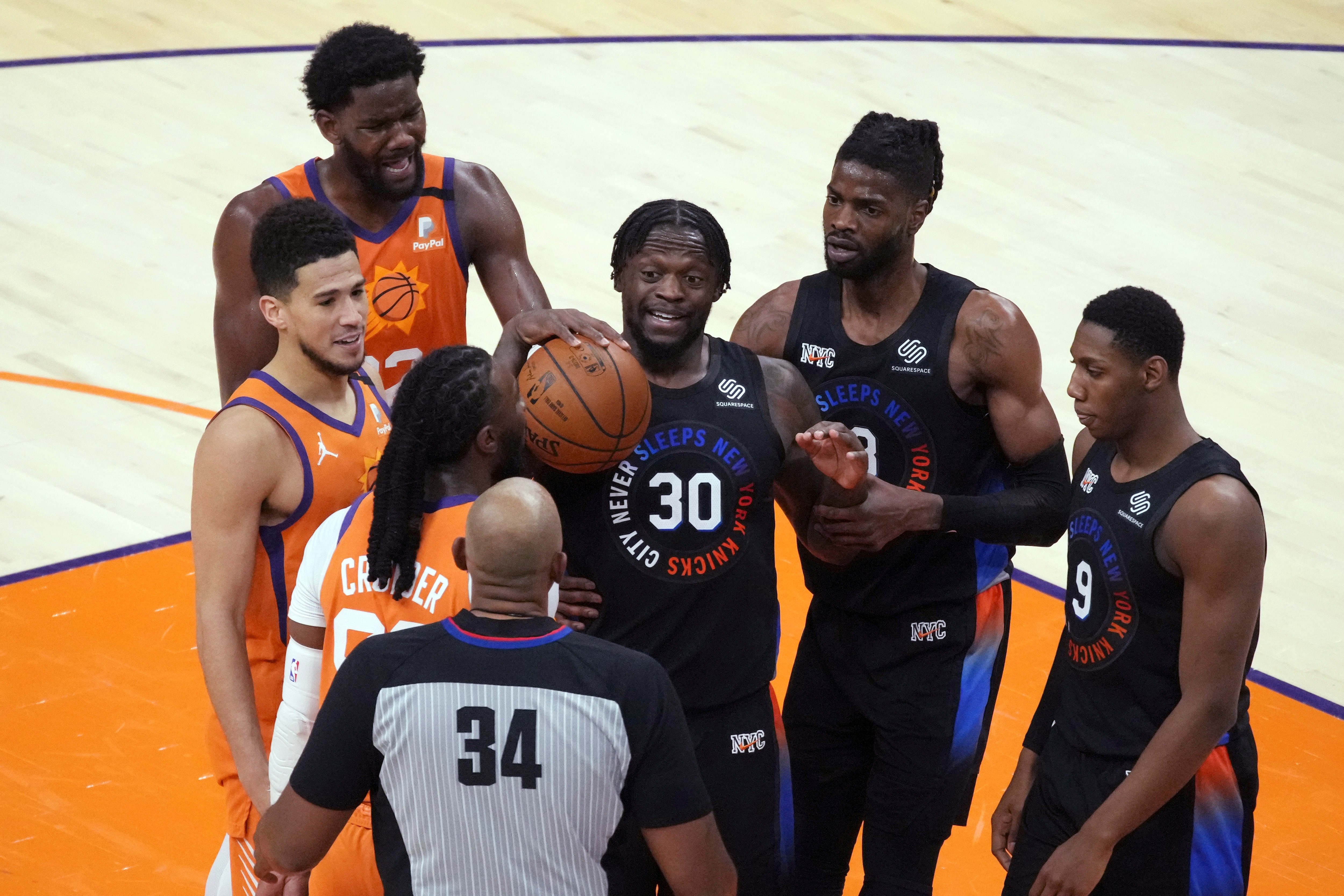 New York Knicks forward Julius Randle (30) stands near center Nerlens Noel (3) and guard RJ Barrett (9) and Phoenix Suns guard Devin Booker and center Deandre Ayton (22) after getting called for a technical foul by referee Kevin Cutler during the second half of an NBA basketball game Friday, May 7, 2021, in Phoenix. Phoenix won 128-105. (AP Photo/Rick Scuteri)