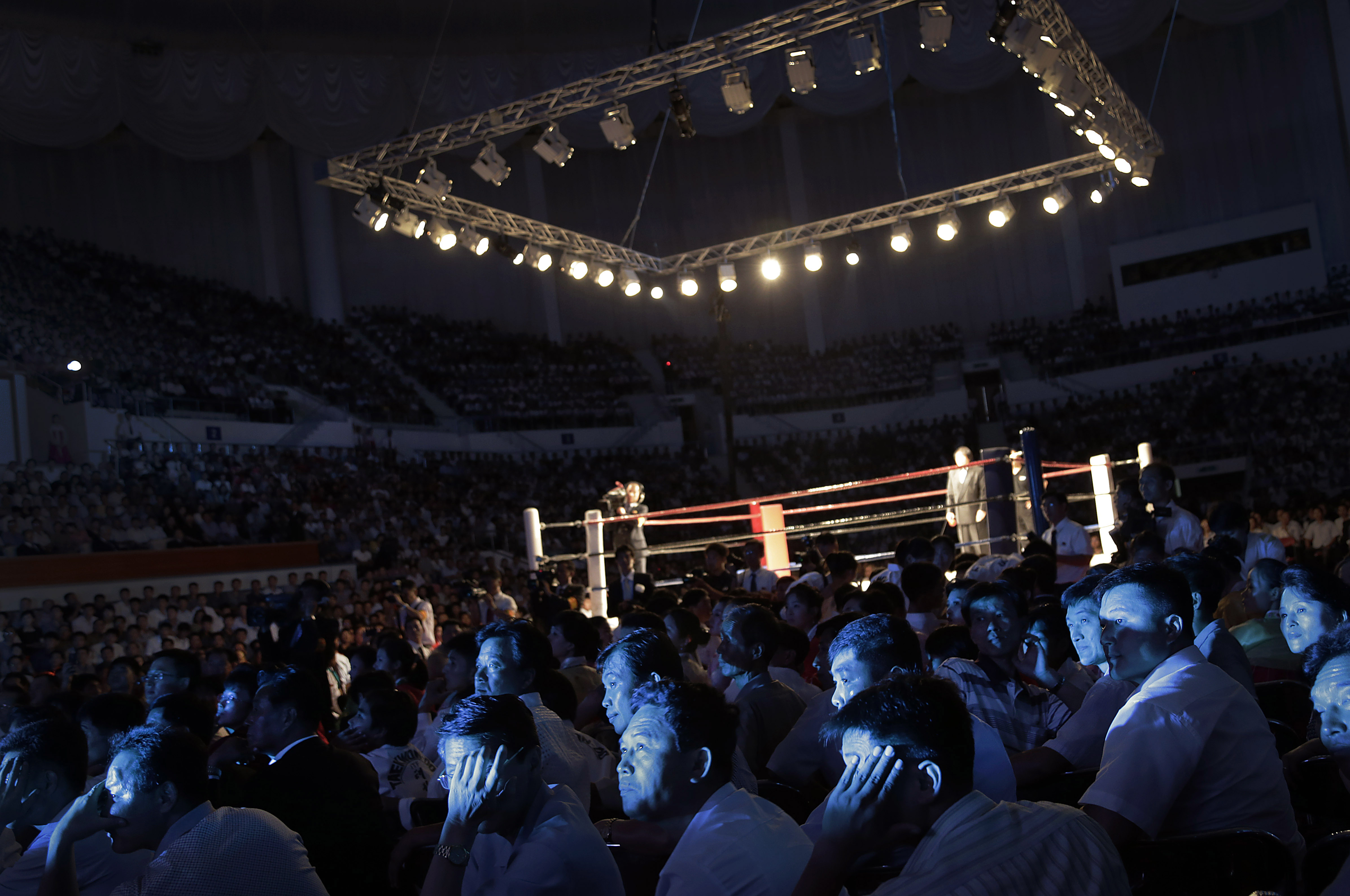 The faces of North Koreans are illuminated by stage lighting as they watch pro wrestlers enter the arena, Saturday, Aug. 30, 2014 in Pyongyang, North Korea. North Koreans got their first look at pro wrestling in about 20-years on Saturday when former NFL lineman Bob "The Beast" Sapp, and 20 other fighters from around the world took to the ring for an exhibition in Pyongyang, put together by colourful Japanese pro-wrestler Kanji "Antonio" Inoki, who is now a member of parliament. (AP Photo/Wong Maye-E)