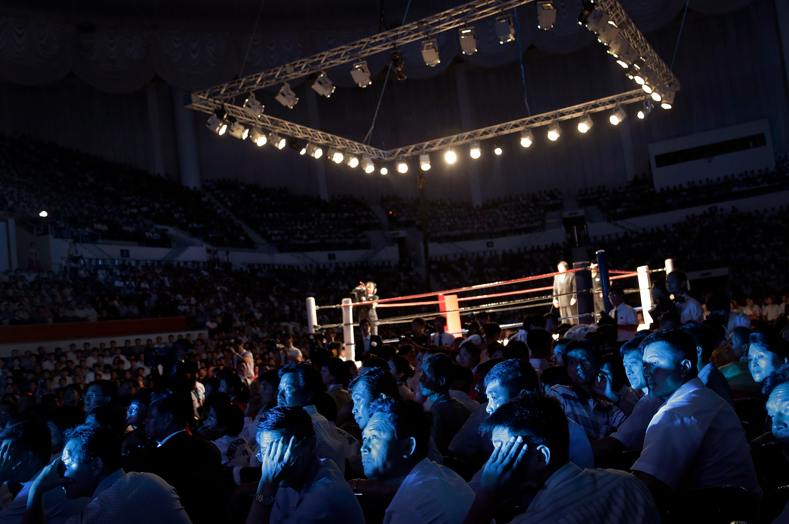 The faces of North Koreans are illuminated by stage lighting as they watch pro wrestlers enter the arena, Saturday, Aug. 30, 2014 in Pyongyang, North Korea. North Koreans got their first look at pro wrestling in about 20-years on Saturday when former NFL lineman Bob "The Beast" Sapp, and 20 other fighters from around the world took to the ring for an exhibition in Pyongyang, put together by colourful Japanese pro-wrestler Kanji "Antonio" Inoki, who is now a member of parliament. (AP Photo/Wong Maye-E)