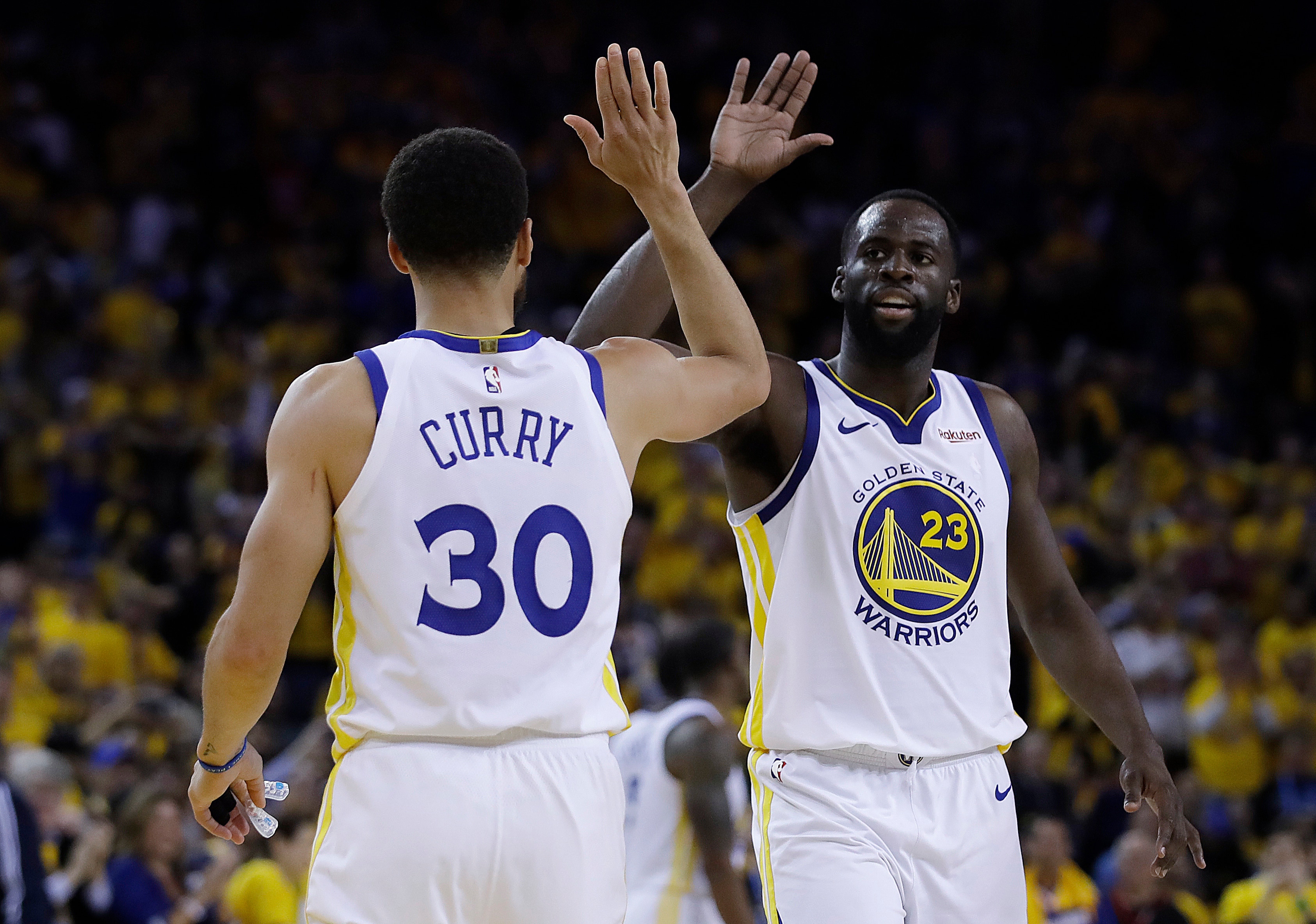 Golden State Warriors' Draymond Green, right, celebrates with Stephen Curry (30) during the final minutes of Game 1 of the team's NBA basketball playoffs Western Conference finals against the Portland Trail Blazers on Tuesday, May 14, 2019, in Oakland, Calif. (AP Photo/Ben Margot)