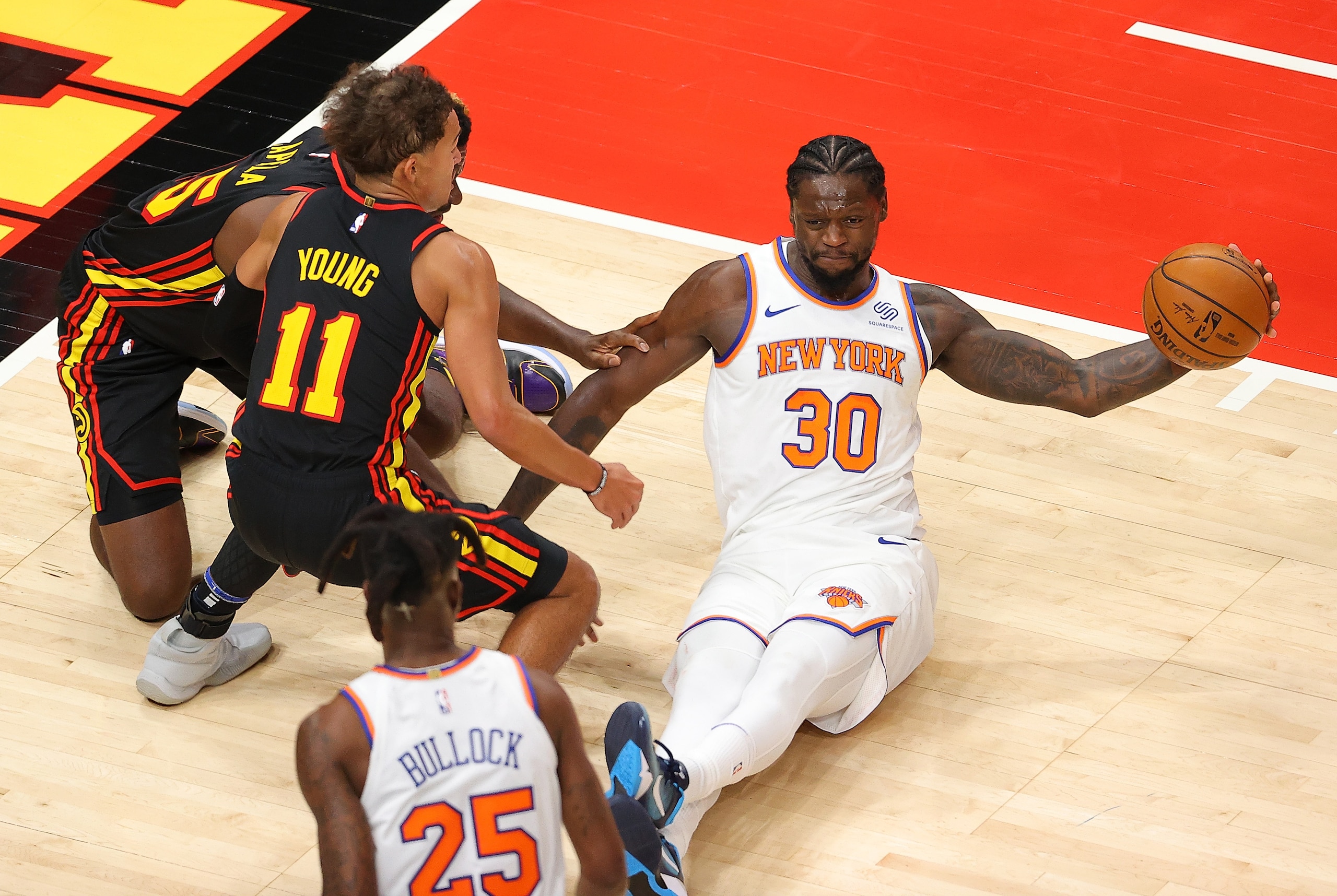 ATLANTA, GEORGIA - JANUARY 04:  Julius Randle #30 of the New York Knicks grabs a loose ball against Trae Young #11 and Clint Capela #15 of the Atlanta Hawks during the second half at State Farm Arena on January 04, 2021 in Atlanta, Georgia.  NOTE TO USER: User expressly acknowledges and agrees that, by downloading and or using this photograph, User is consenting to the terms and conditions of the Getty Images License Agreement.  (Photo by Kevin C. Cox/Getty Images)