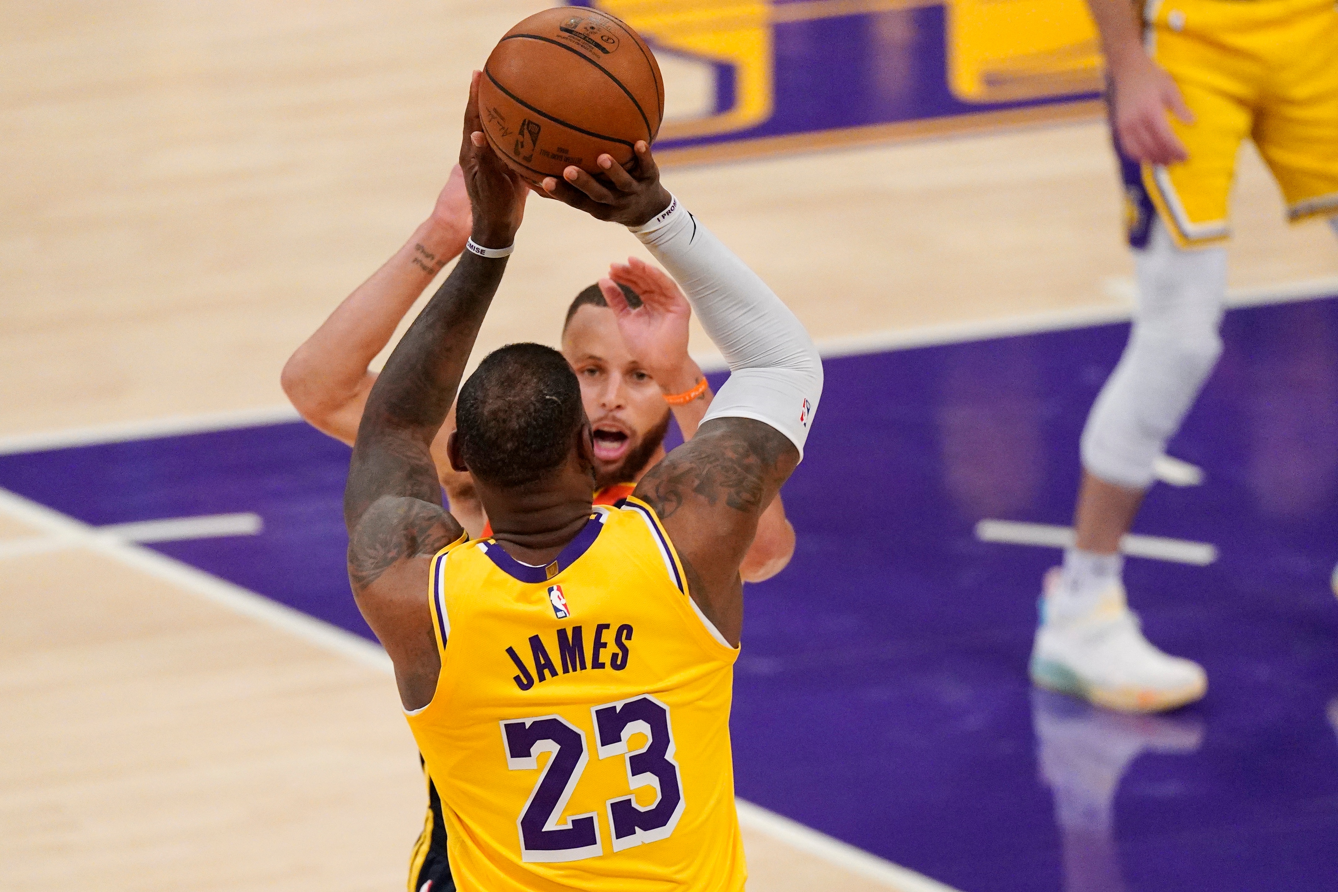 Los Angeles Lakers forward LeBron James, below, shoots and makes a three-point shot as Golden State Warriors guard Stephen Curry defends with one minute left in an NBA basketball Western Conference Play-In game Wednesday, May 19, 2021, in Los Angeles. (AP Photo/Mark J. Terrill)