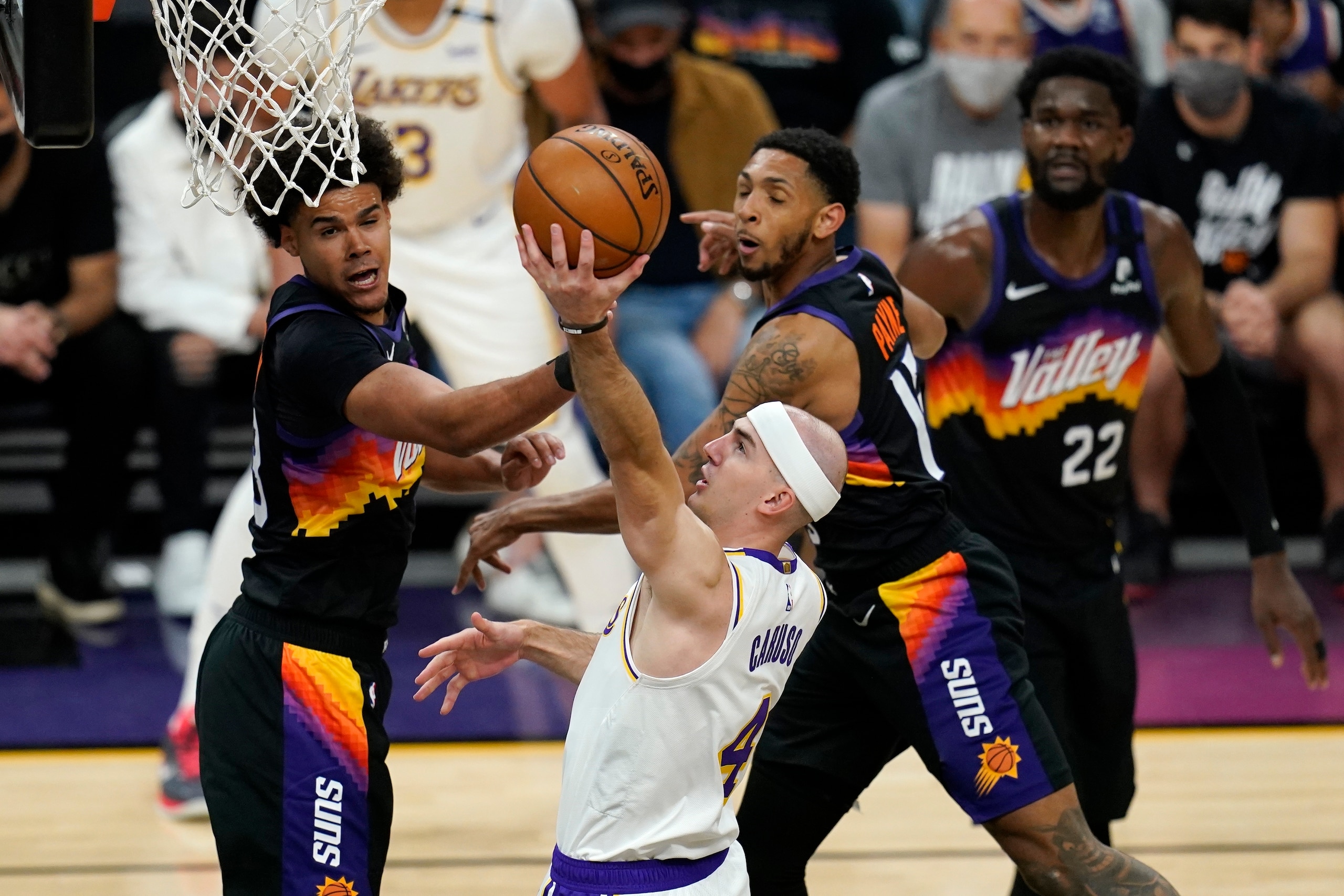 Los Angeles Lakers guard Alex Caruso (4) drives past Phoenix Suns forward Cameron Johnson, left, guard Cameron Payne, second from right, and center Deandre Ayton (22) during the first half of Game 1 of their NBA basketball first-round playoff series Sunday, May 23, 2021, in Phoenix. (AP Photo/Ross D. Franklin)