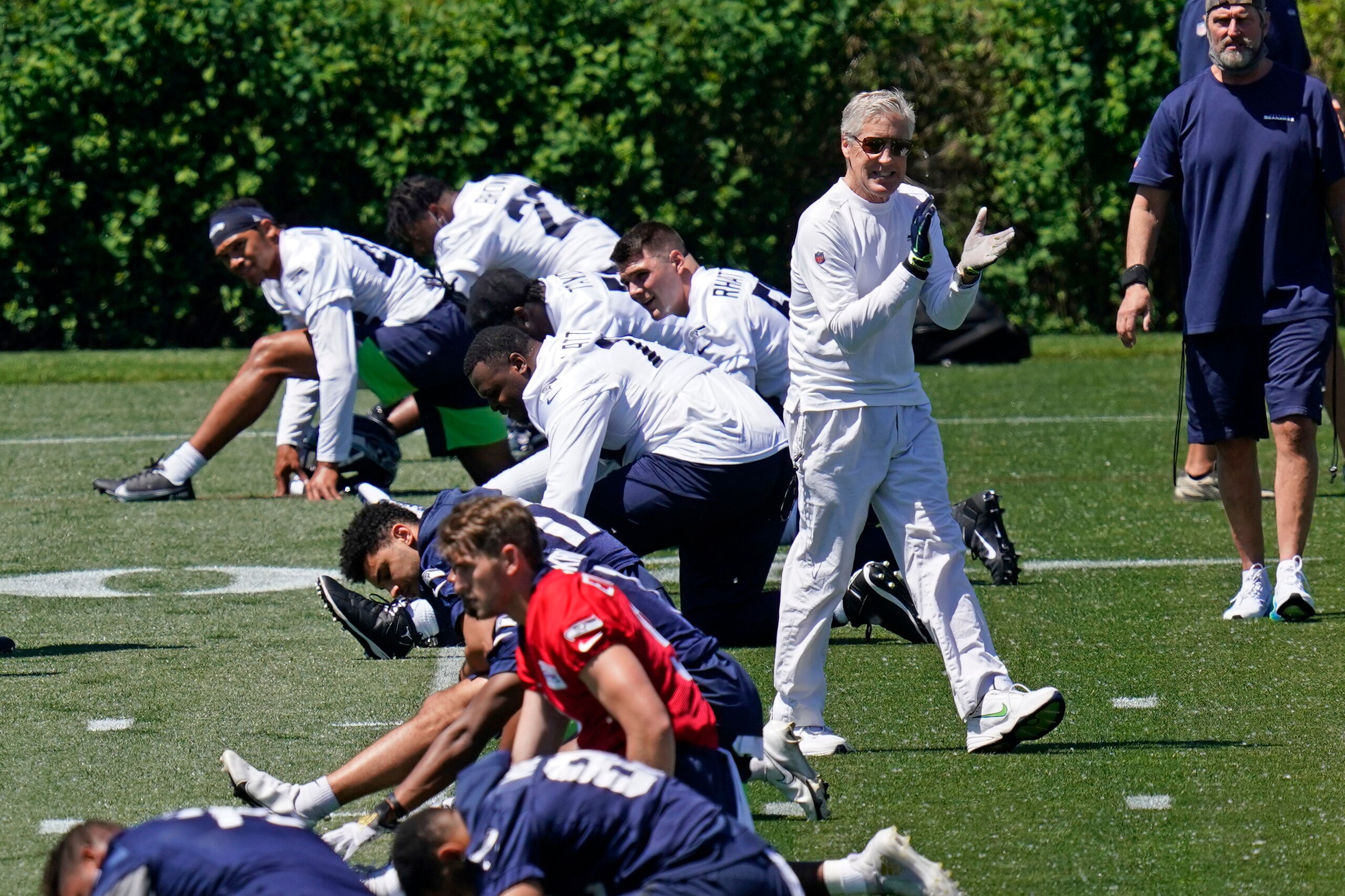 Seattle Seahawks head coach Pete Carroll claps his hands as he walks past players stretching during an NFL football rookie minicamp Friday, May 14, 2021, at the team's training facility in Renton, Wash. (AP Photo/Elaine Thompson)