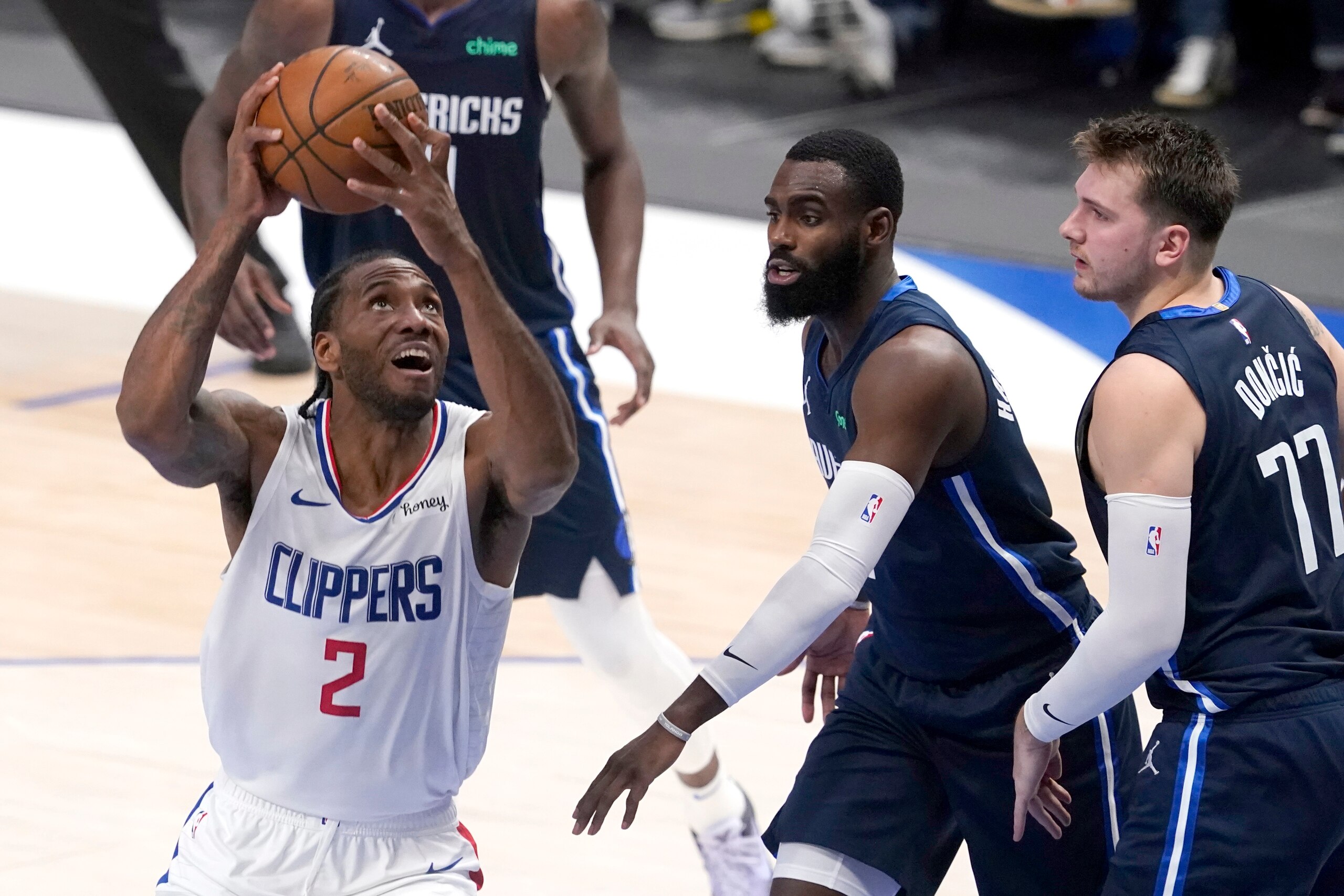 Los Angeles Clippers forward Kawhi Leonard (2) positions for a shot as Dallas Mavericks' Tim Hardaway Jr., center, and Luka Doncic (77) defend in the first half in Game 3 of an NBA basketball first-round playoff series in Dallas, Friday, May 28, 2021. (AP Photo/Tony Gutierrez)