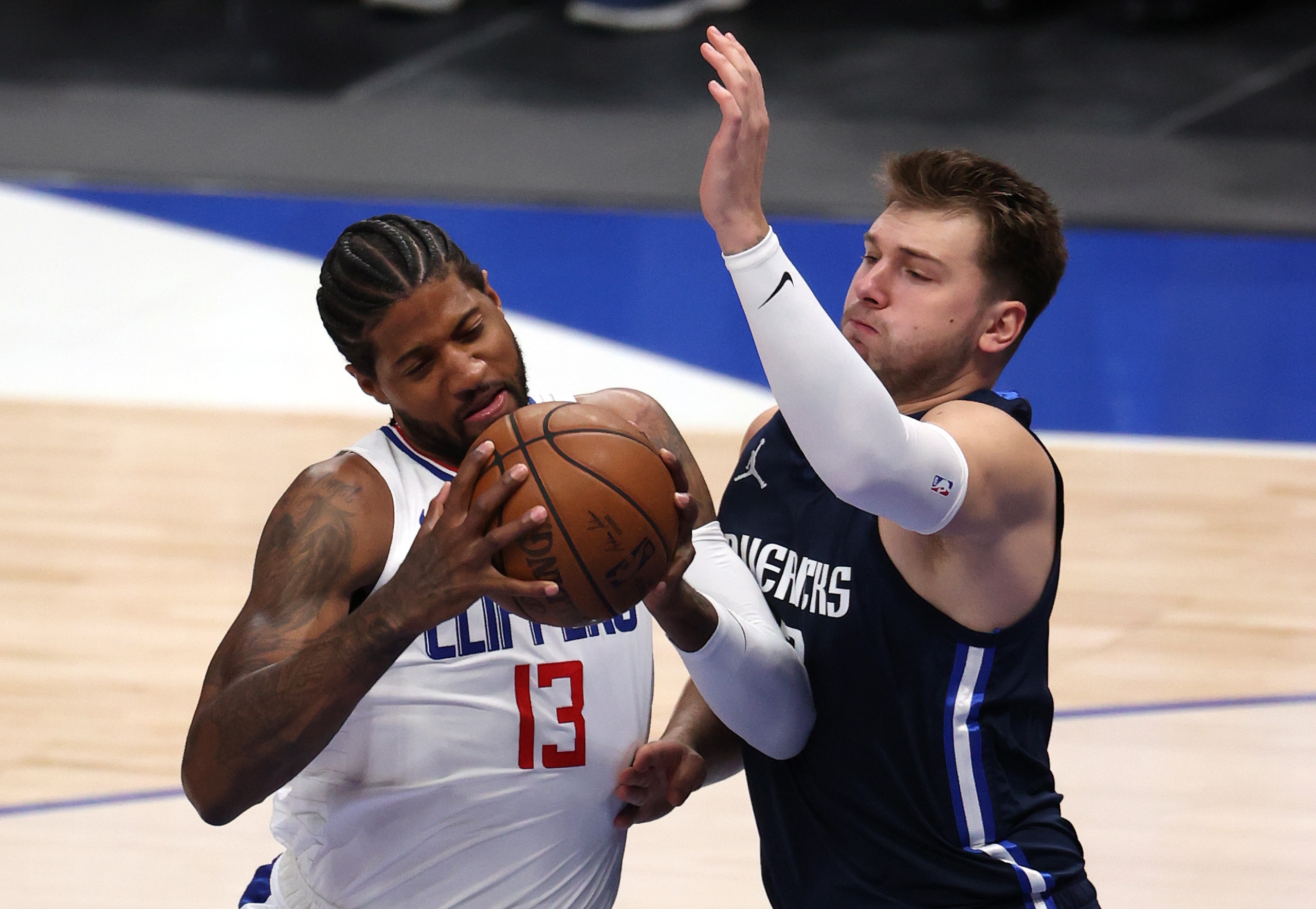DALLAS, TEXAS - MAY 28:  Paul George #13 of the LA Clippers controls the ball against Luka Doncic #77 of the Dallas Mavericks in the first quarter in game three of the Western Conference first round series at American Airlines Center on May 28, 2021 in Dallas, Texas.  NOTE TO USER: User expressly acknowledges and agrees that, by downloading and or using this photograph, User is consenting to the terms and conditions of the Getty Images License Agreement. (Photo by Ronald Martinez/Getty Images)