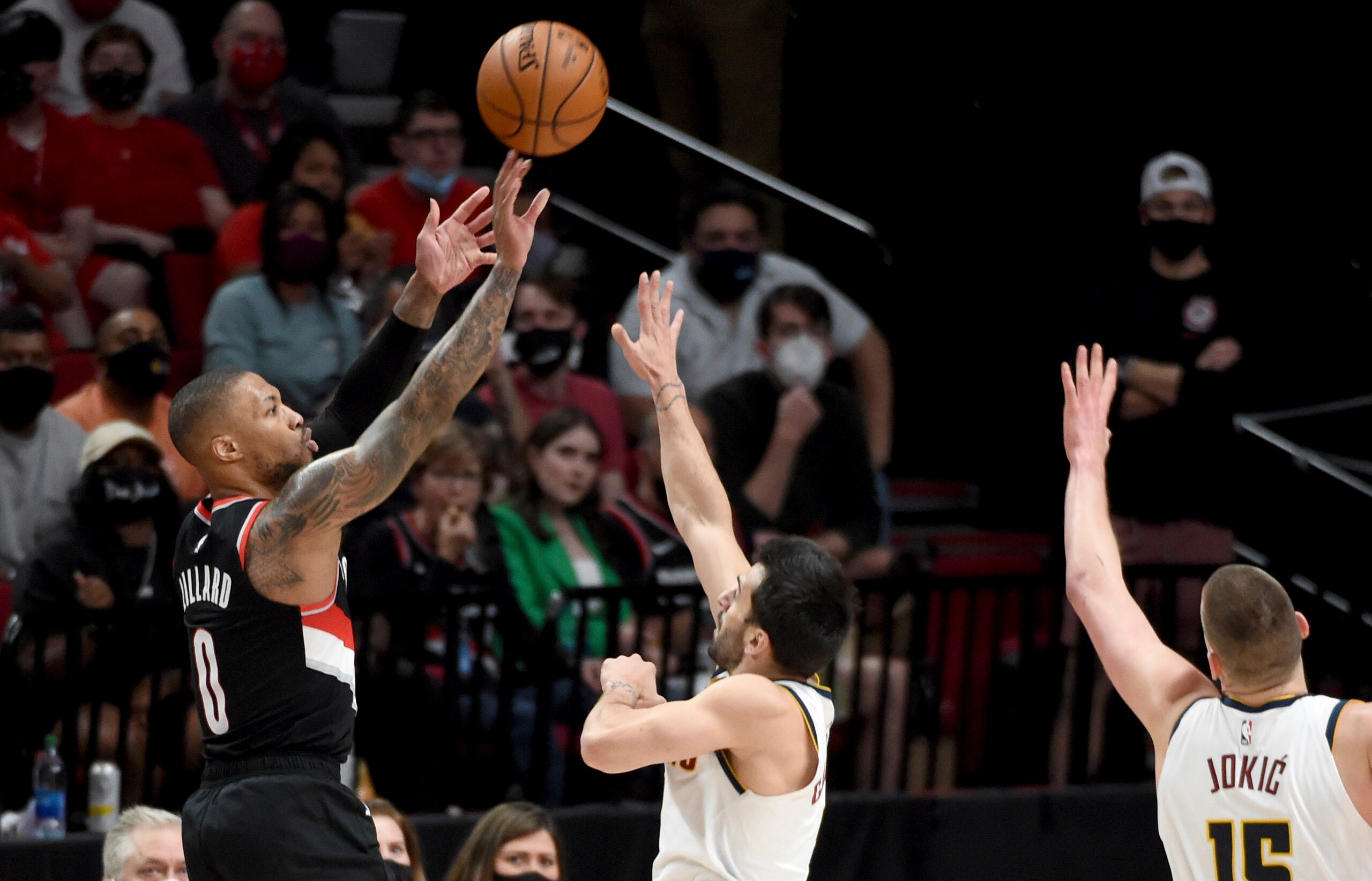 Portland Trail Blazers guard Damian Lillard, left, hits a shot over Denver Nuggets guard Facundo Campazzo, center, and center Nikola Jokic, right, during the first half of Game 4 of an NBA basketball first-round playoff series in Portland, Ore., Saturday, May 29, 2021. (AP Photo/Steve Dykes)