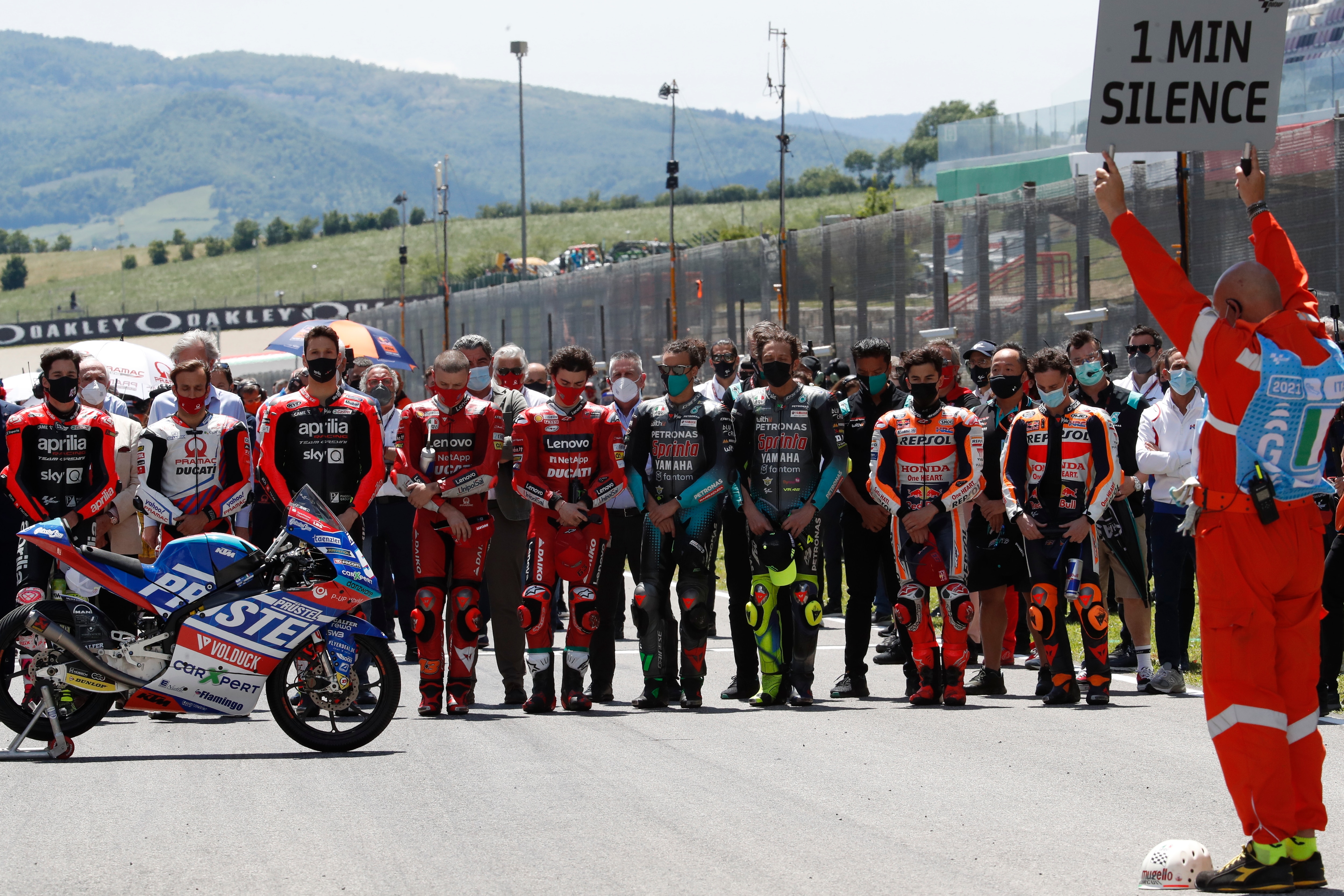 Teammates of 19 years-old Swiss rider Jason Dupasquier and riders from other teams stand near his motorbike as they pay a minute of silence in his memory prior to the start of the Motogp Grand Prix of Italy at the Mugello circuit, in Scarperia, Italy, Sunday, May 30, 2021. Dupasquier died Sunday after being hospitalized Saturday, at the Florence hospital following his crash during the qualifying practices of the Moto3. (AP Photo/Antonio Calanni)