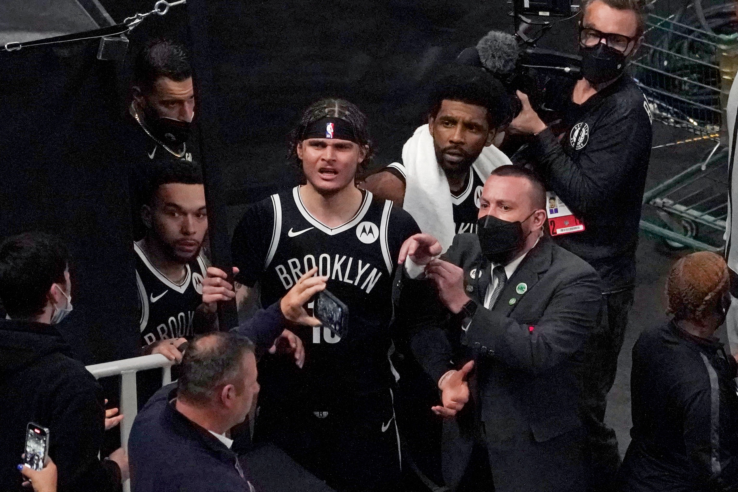 A security guard points as Brooklyn Nets' Kyrie Irving, right with towel, and teammates look up at a fan who reportedly threw a water bottle at him as he left the court after Game 4 during an NBA basketball first-round playoff series, Sunday, May 30, 2021, in Boston. (AP Photo/Elise Amendola)