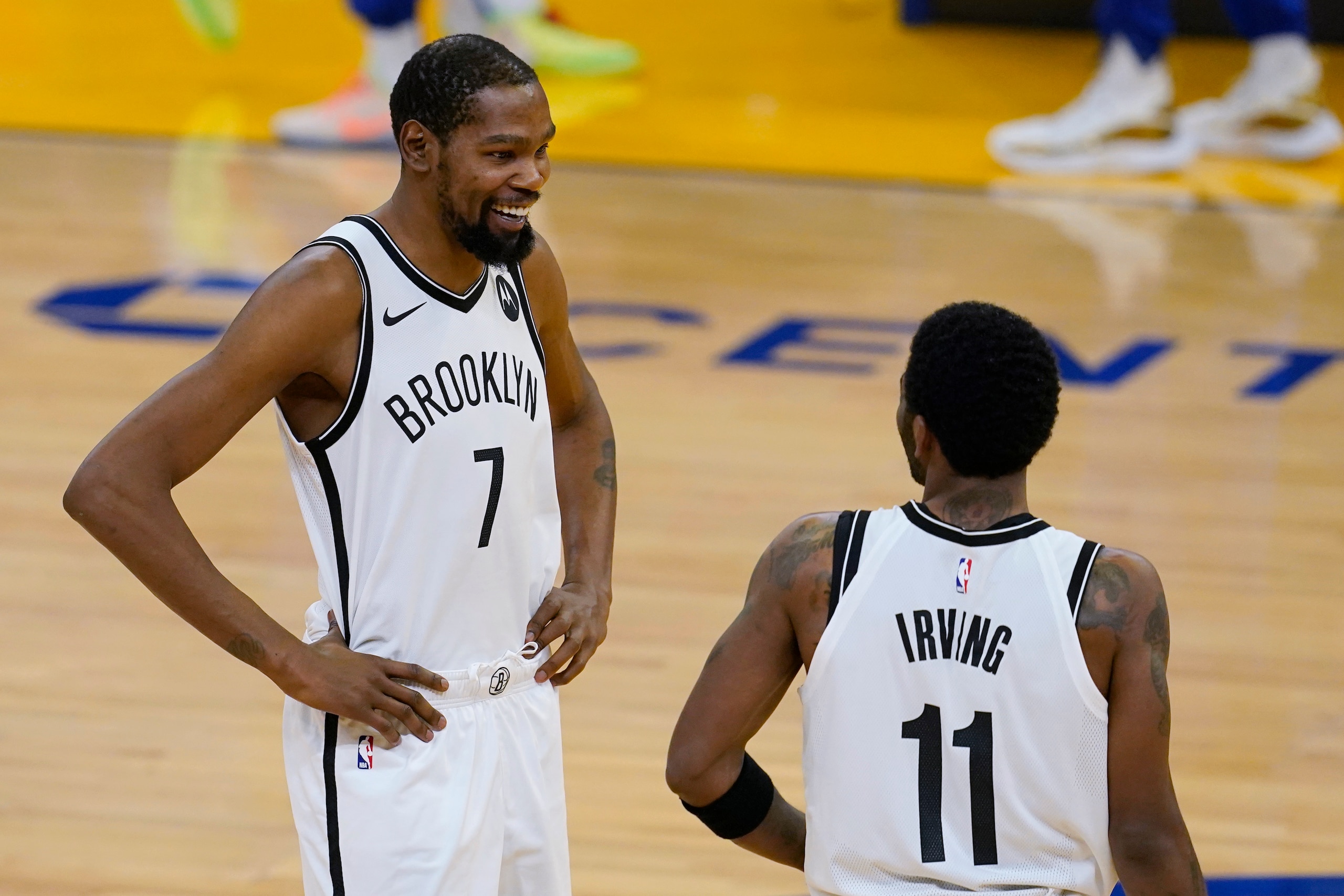 Brooklyn Nets forward Kevin Durant (7) smiles while talking with guard Kyrie Irving (11) before the team's NBA basketball game against the Golden State Warriors in San Francisco, Saturday, Feb. 13, 2021. (AP Photo/Jeff Chiu)