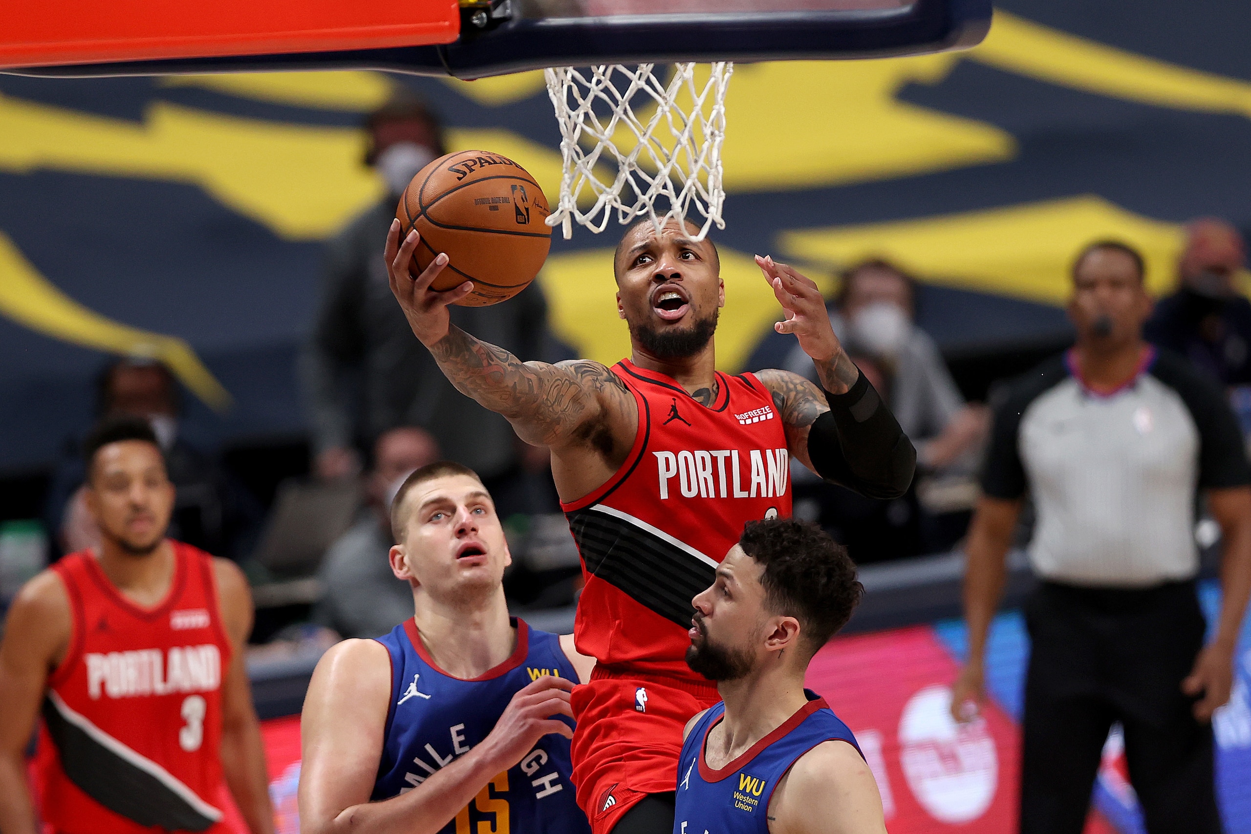 DENVER, COLORADO - JUNE 01: Damian Lillard #0 of the Portland Trail Blazers goes to the basket against Nikola Jokic #15 and Austin Rivers #25 of the Denver Nuggets in the first overtime during Game Five of their Western Conference first-round playoff series at Ball Arena on June 1, 2021 in Denver, Colorado. NOTE TO USER: User expressly acknowledges and agrees that, by downloading and or using this photograph, User is consenting to the terms and conditions of the Getty Images License Agreement (Photo by Matthew Stockman/Getty Images)