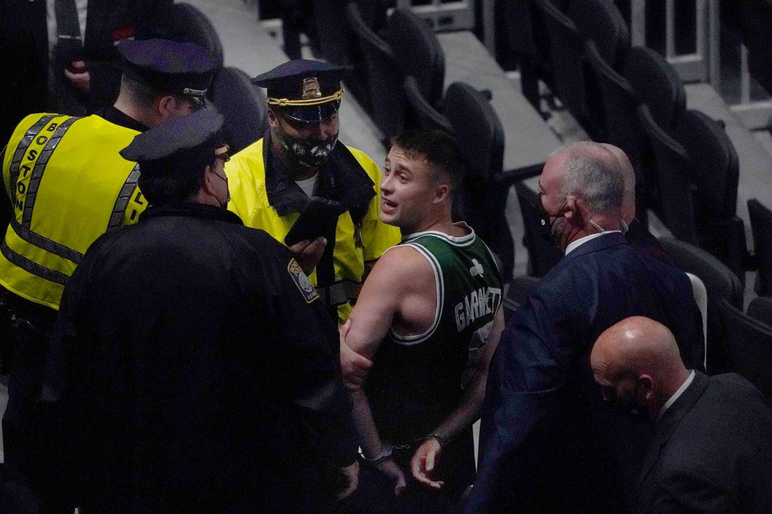 A fan is handcuffed and escorted out of TD Garden by police after allegedly throwing a water bottle at Brooklyn Nets' Kyrie Irving as Irving left the court after Game 4 of an NBA basketball first-round playoff series, Sunday, May 30, 2021, in Boston. The Nets won 141-126. (AP Photo/Elise Amendola)