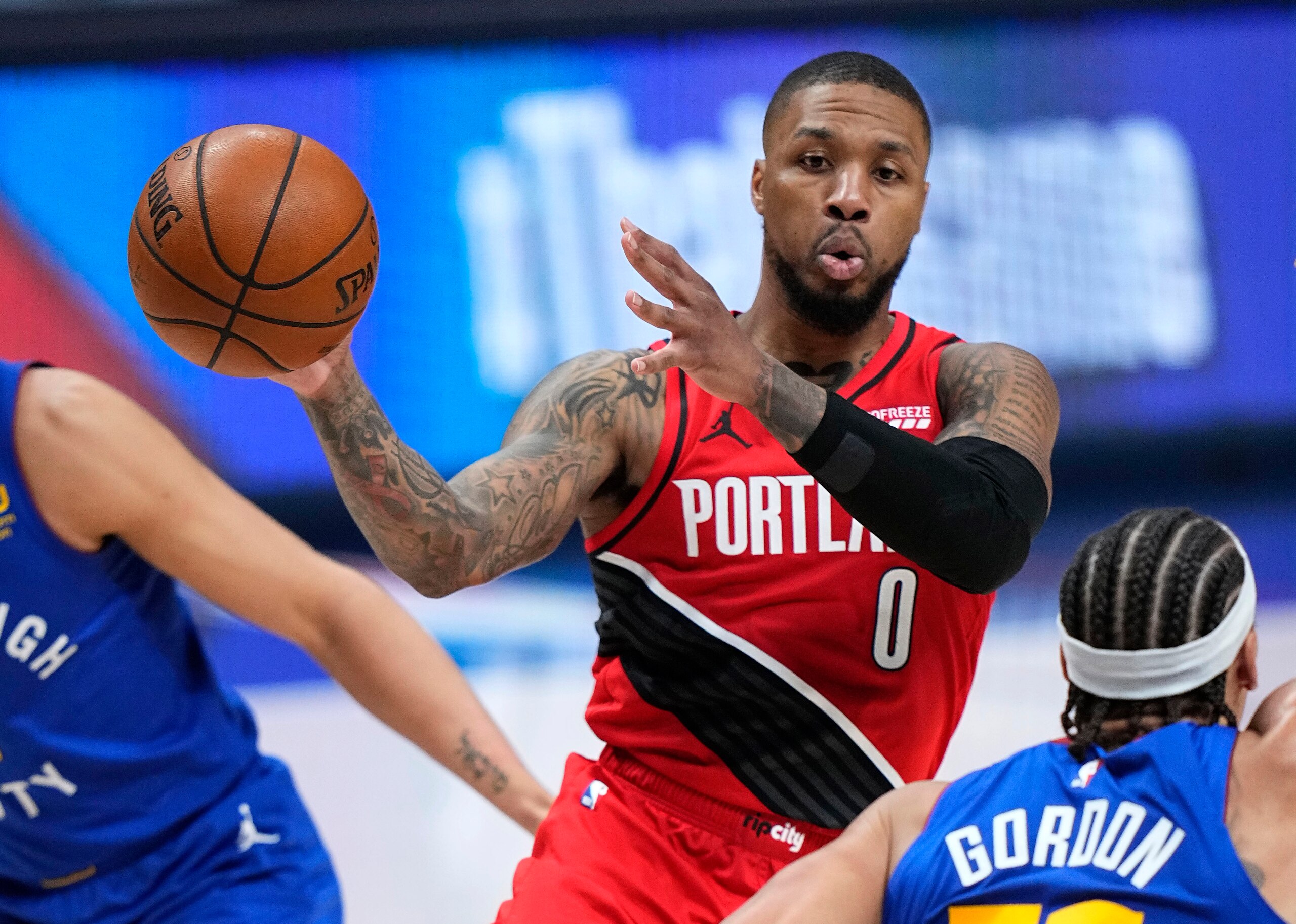 El jugador de los Trail Blazers de Portland Damian Lillard (0) pasa el balón a los Nuggets de Denver en la segunda mitad del primer juego de su serie de primera ronda de playoffs de la NBA, el sábado 22 de mayo de 2021 en Denver, Colorado. (AP Foto/Jack Dempsey)