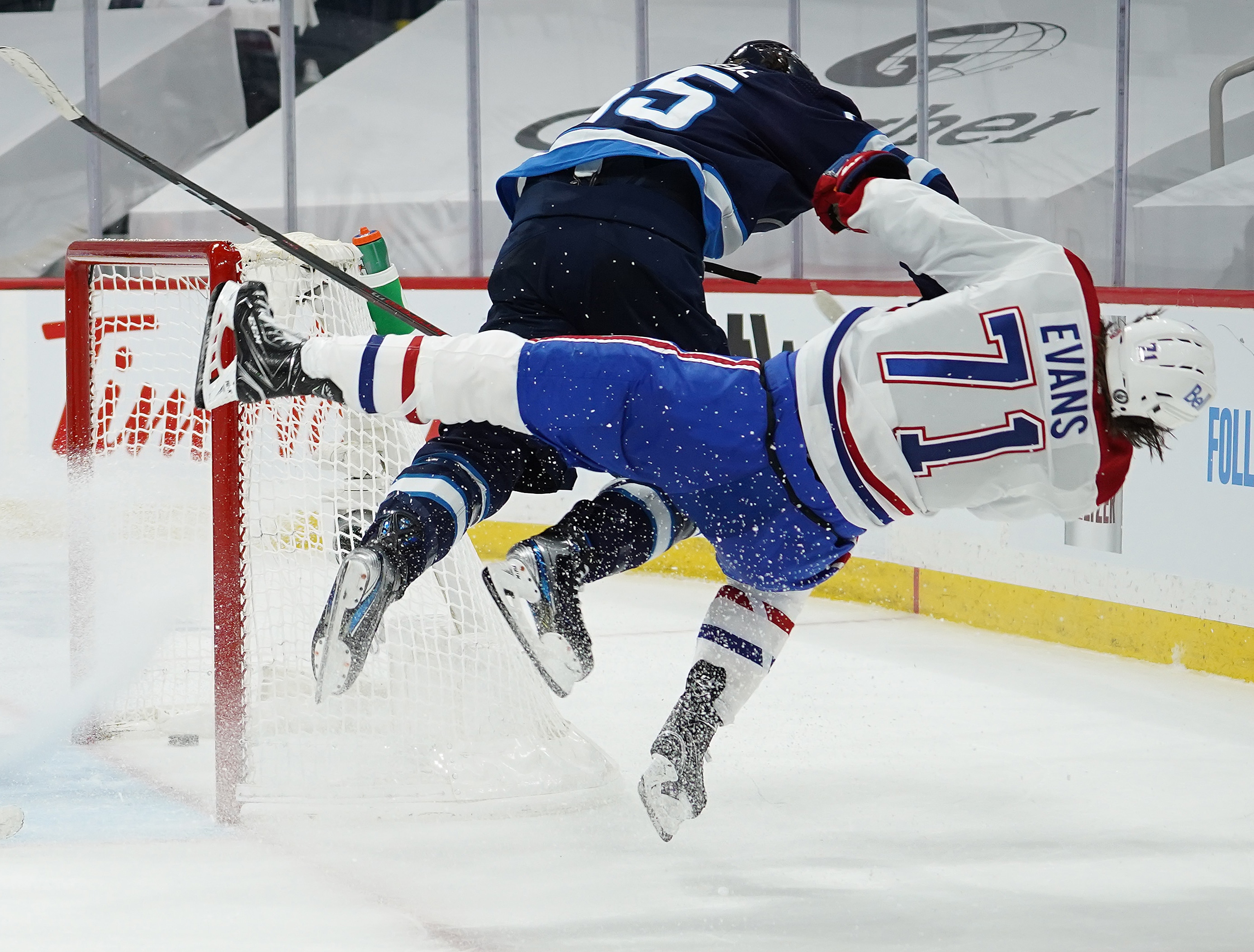 WINNIPEG, MB - JUNE 2: Jake Evans #71 of the Montreal Canadiens is checked hard by Mark Scheifele #55 of the Winnipeg Jets after Evans's third-period empty-net goal in Game One of the Second Round of the 2021 Stanley Cup Playoffs on June 2, 2021 at Bell MTS Place in Winnipeg, Manitoba, Canada. Evans was injured on the play.  (Photo by David Lipnowski/Getty Images)