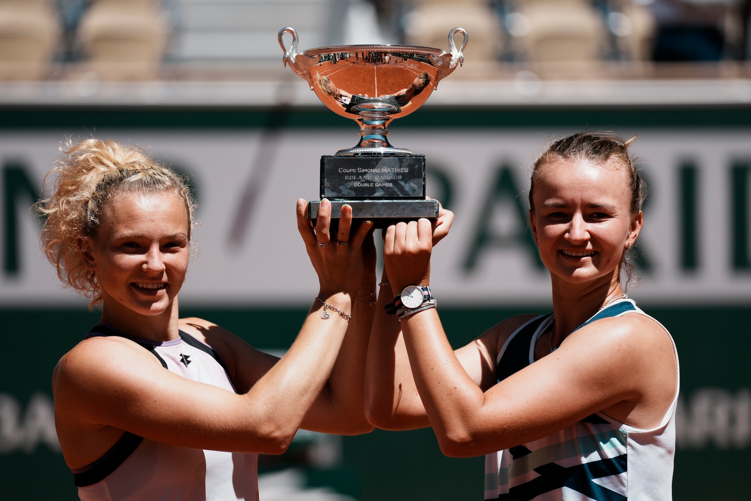 Czech Republic's Barbora Krejcikova, right, and compatriot Katerina Siniakova hold the cup after defeating USA's Bethanie Mattek-Sands and Poland's Iga Swiatek in their women's doubles final match of the French Open tennis tournament at the Roland Garros stadium Sunday, June 13, 2021 in Paris. (AP Photo/Thibault Camus)