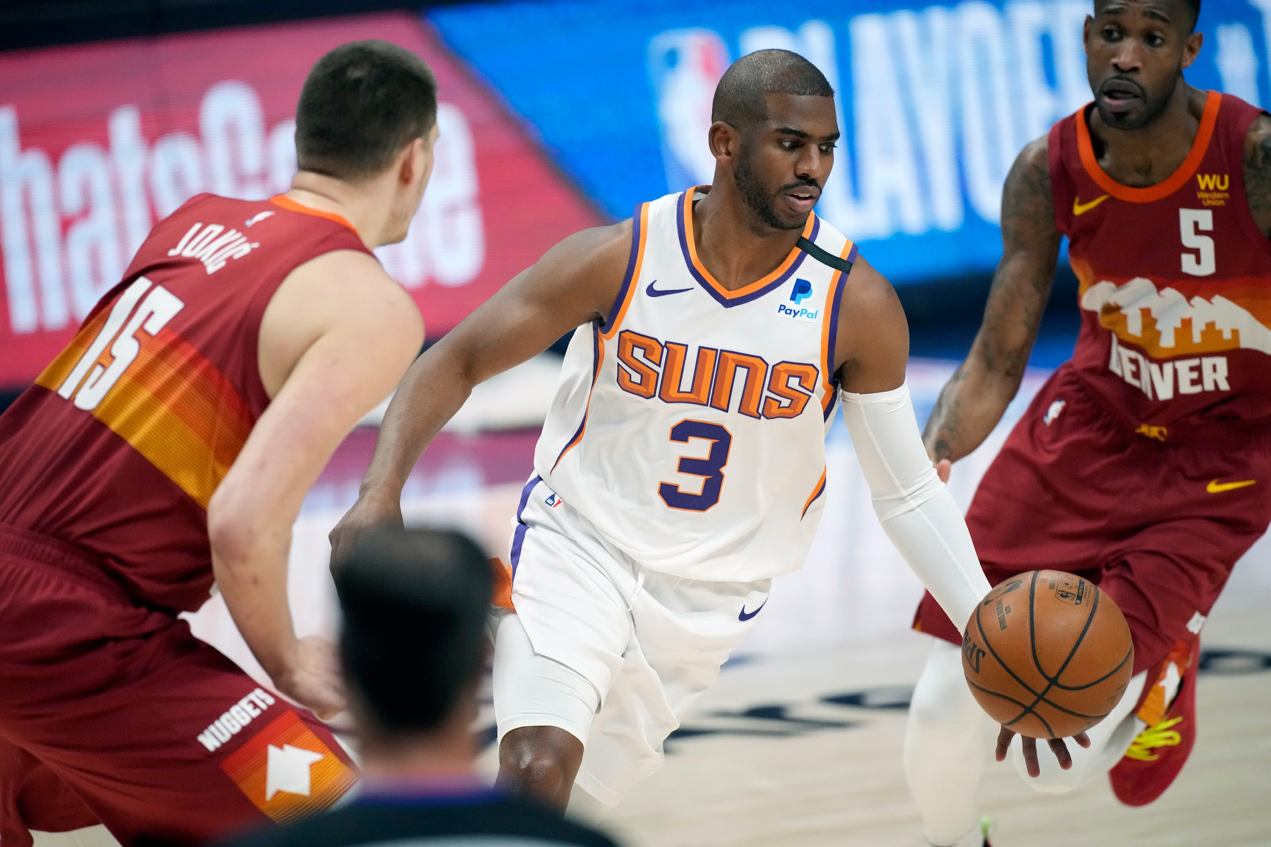Phoenix Suns guard Chris Paul, center, drives to the rim between Denver Nuggets center Nikola Jokic, left, and forward Will Barton in the first half of Game 4 of an NBA second-round playoff series Sunday, June 13, 2021, in Denver. (AP Photo/David Zalubowski)