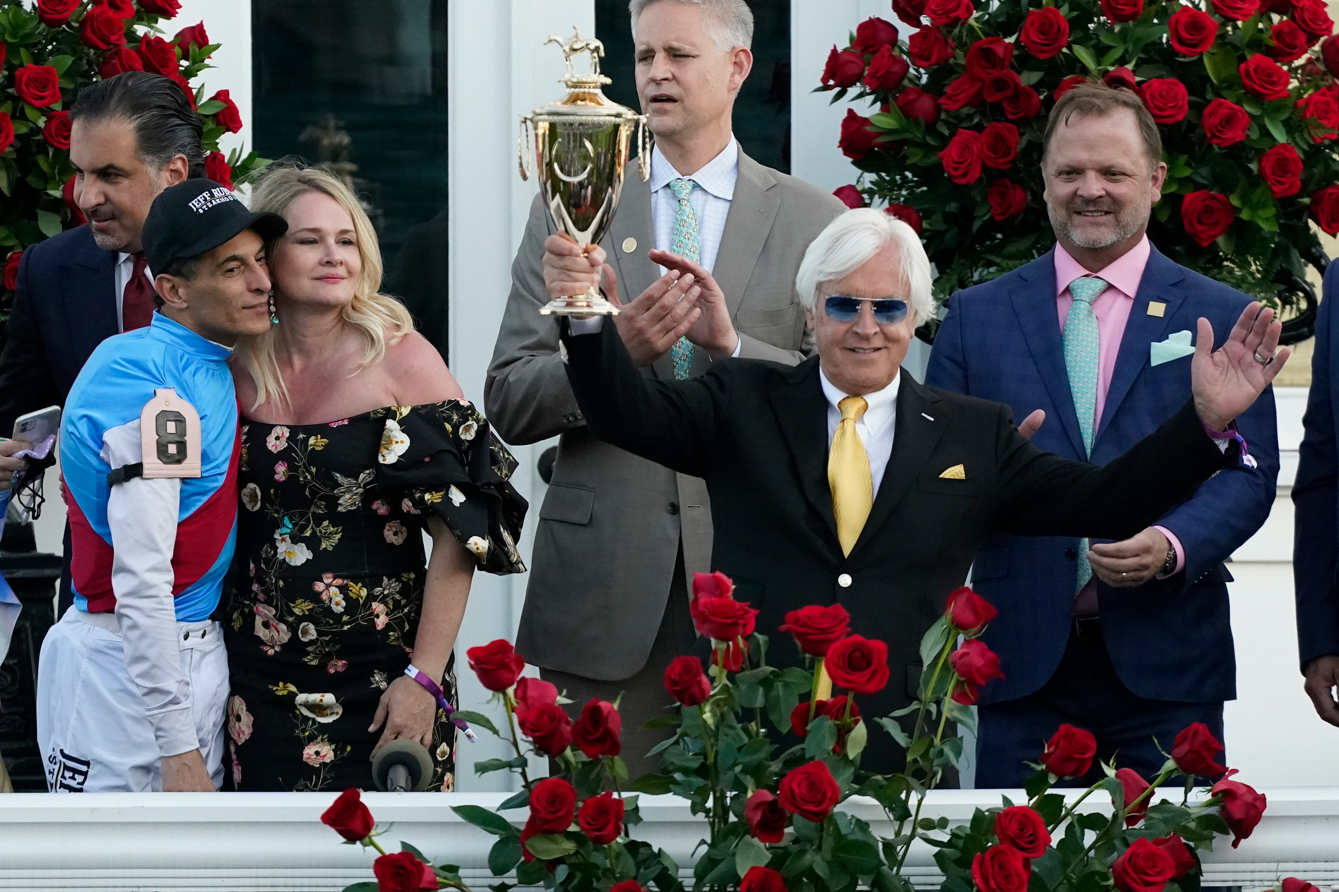 Jockey John Velazquez, left, watches as trainer Bob Baffert holds up the winner's trophy after they victory with Medina Spirit in the 147th running of the Kentucky Derby at Churchill Downs, Saturday, May 1, 2021, in Louisville, Ky. (AP Photo/Jeff Roberson)