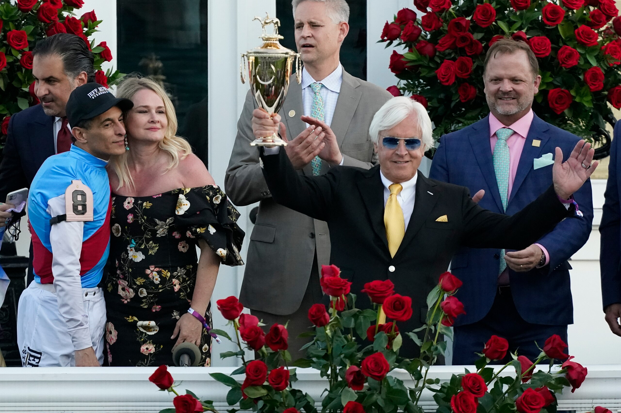 Jockey John Velazquez, left, watches as trainer Bob Baffert holds up the winner's trophy after they victory with Medina Spirit in the 147th running of the Kentucky Derby at Churchill Downs, Saturday, May 1, 2021, in Louisville, Ky. (AP Photo/Jeff Roberson)