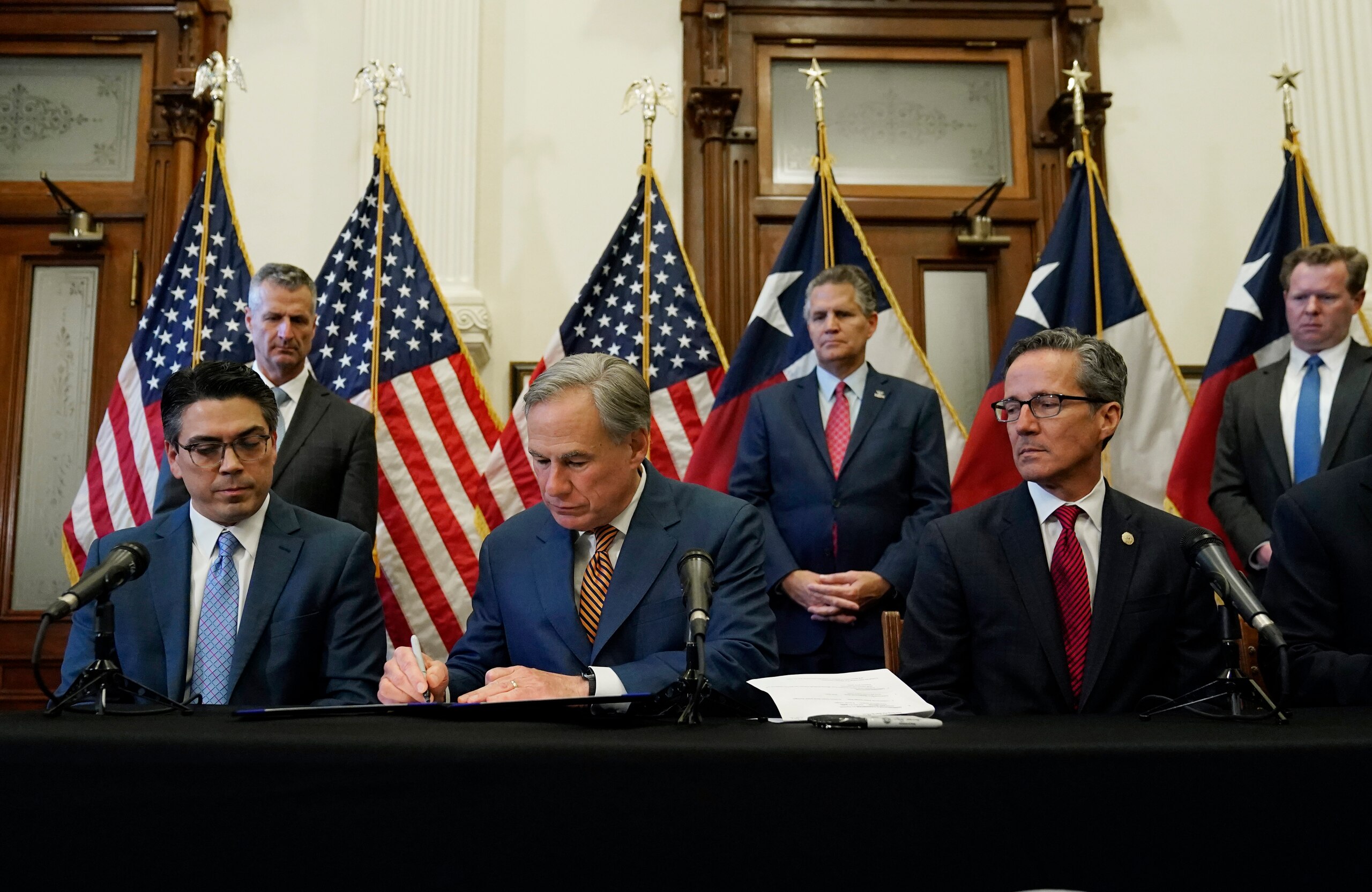 With state Rep. Chris Paddie, left, and state Sen. Kelly Hancock, right, looking on, Texas Gov. Greg Abbott, center, signs two energy related bills, Tuesday, June 8, 2021, in Austin, Texas. Abbot signed legislation into law to reform the Electric Reliability Council of Texas (ERCOT) and weatherize and improve the reliability of the state's power grid. (AP Photo/Eric Gay)