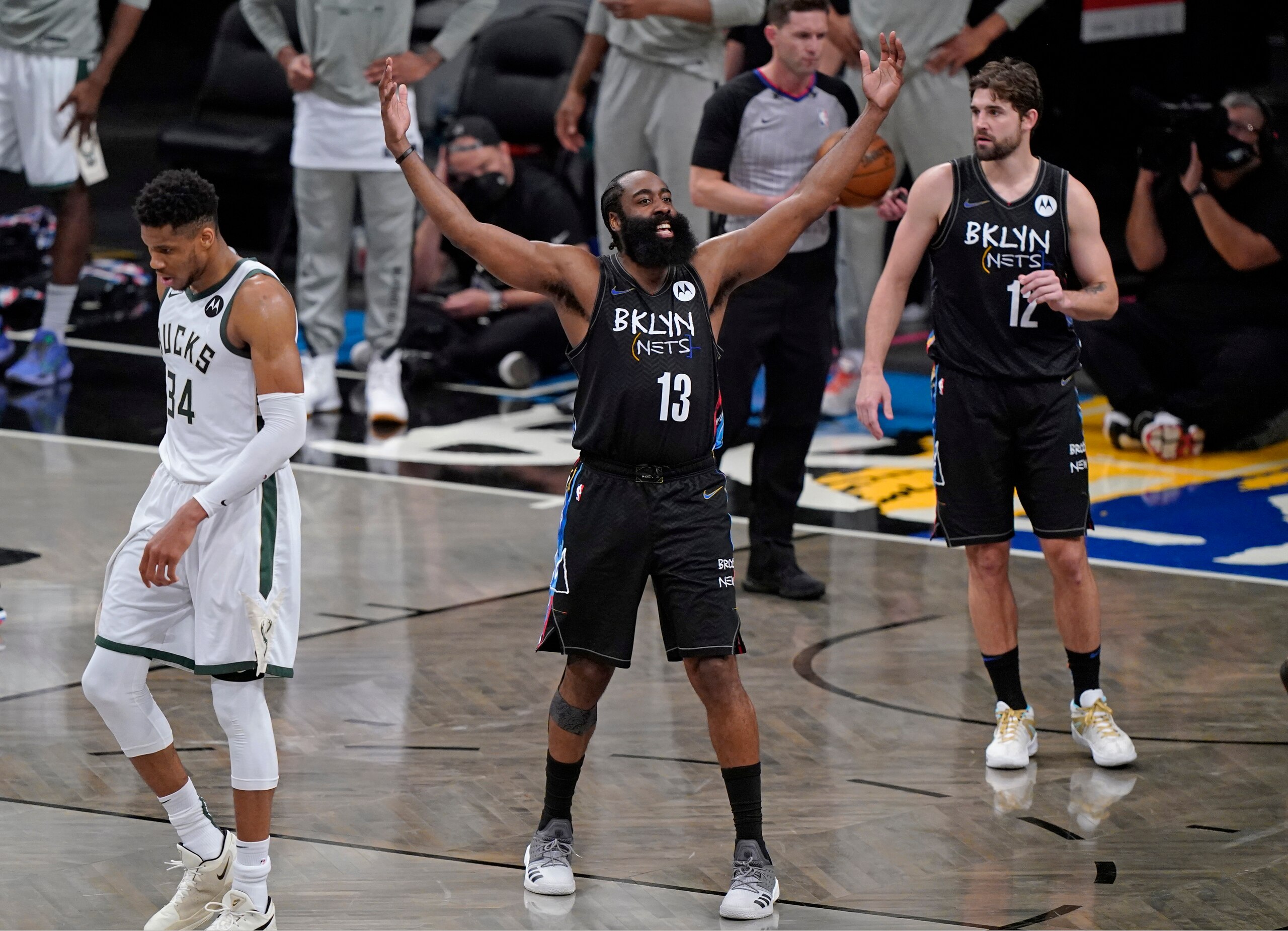 Brooklyn Nets guard James Harden (13) encourages the crowd to get behind the team during the final minutes of Game 5 of a second-round NBA basketball playoff series against the Milwaukee Bucks, Tuesday, June 15, 2021, in New York. Bucks forward Giannis Antetokounmpo (34) walks away. Nets forward Joe Harris is at right. The Nets won 114-108 to take a 3-2 lead in the series. (AP Photo/Kathy Willens)