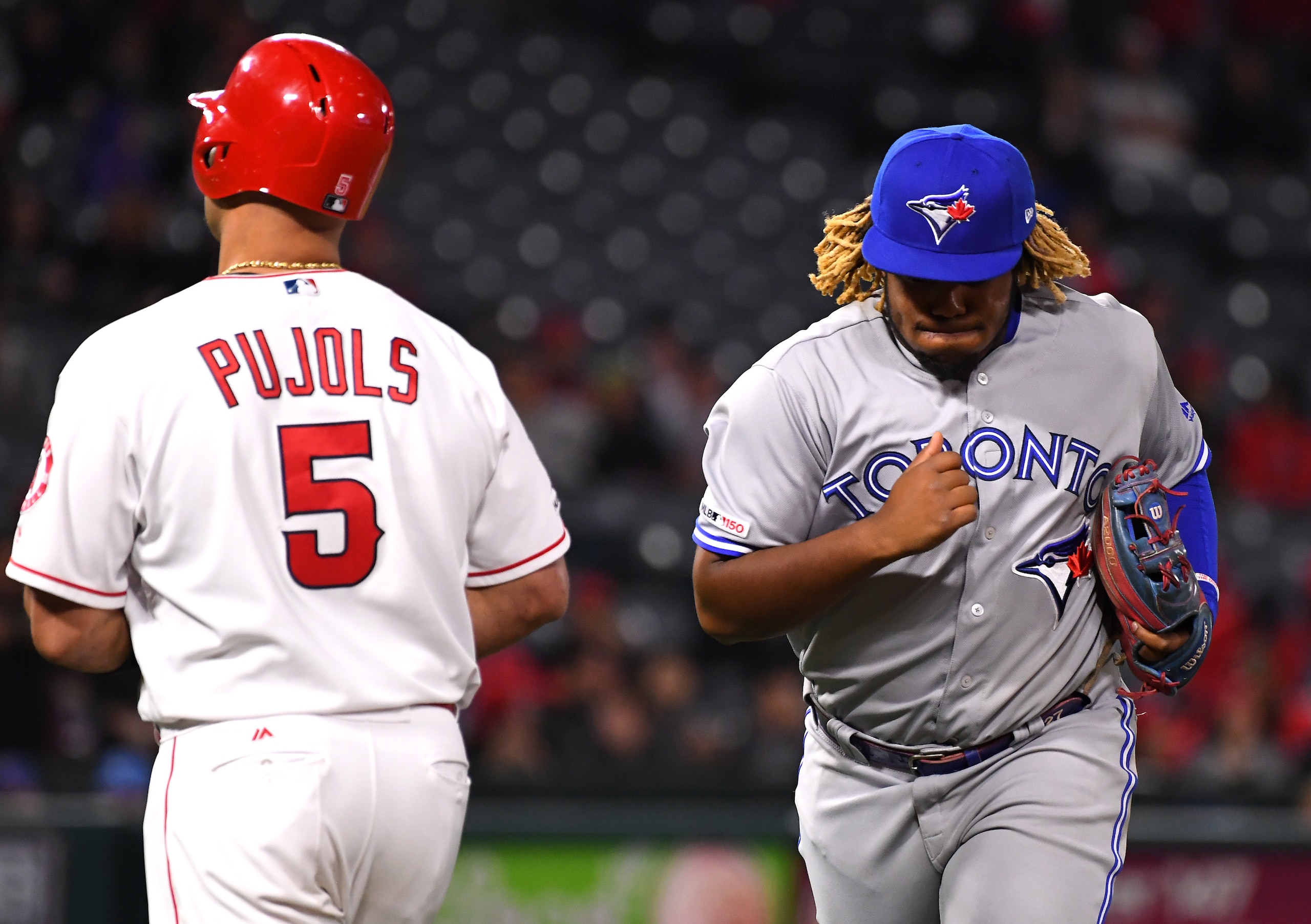 ANAHEIM, CA - MAY 01: Vladimir Guerrero Jr. #27 of the Toronto Blue Jays returns to the dugout after throwing out Albert Pujols #5 of the Los Angeles Angels of Anaheim at first base in the game at Angel Stadium of Anaheim on May 1, 2019 in Anaheim, California. (Photo by Jayne Kamin-Oncea/Getty Images)