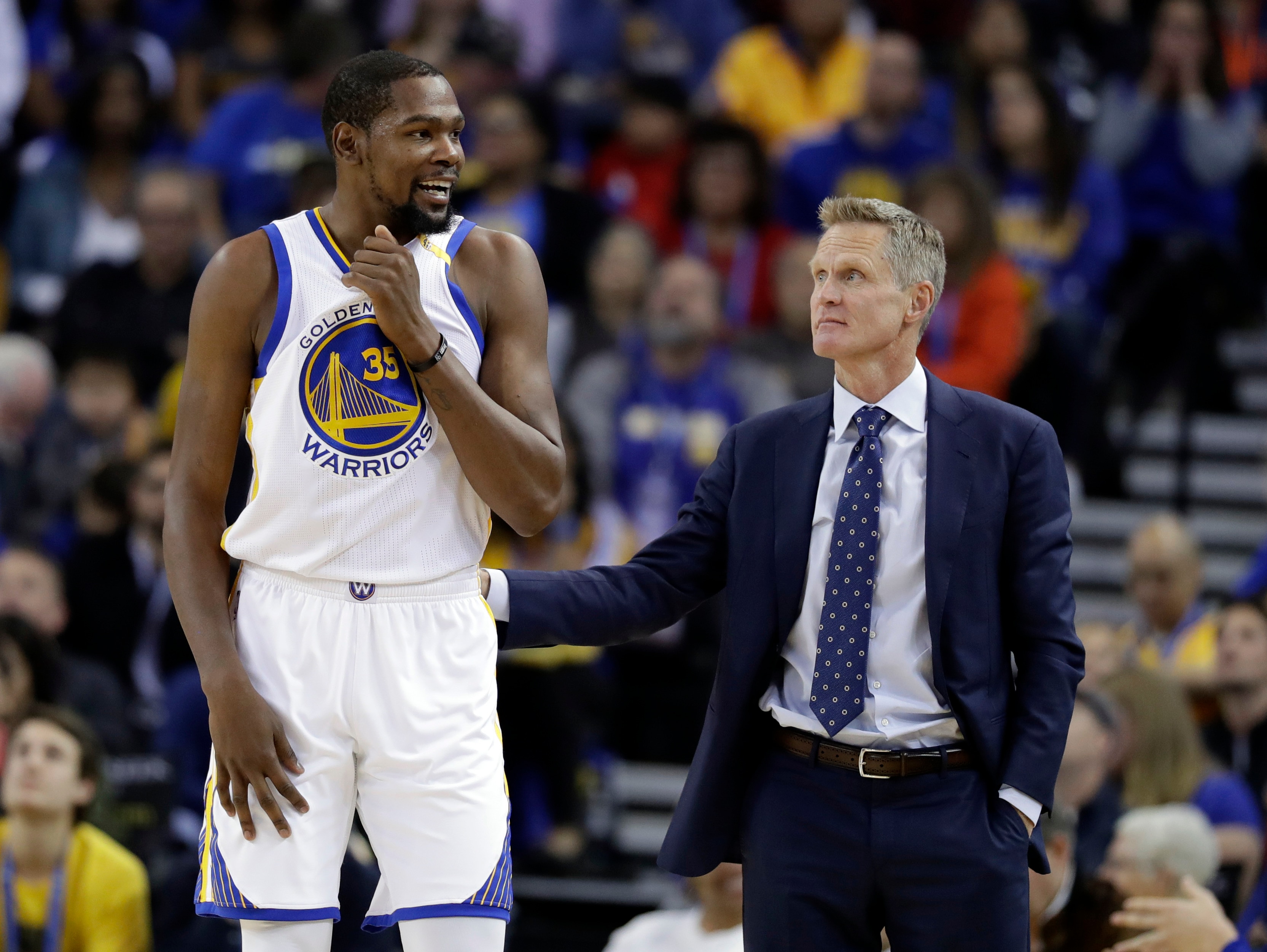FILE - In this Nov. 23, 2016, file photo, Golden State Warriors' Kevin Durant, left, talks with coach Steve Kerr during the team's NBA basketball game against the Los Angeles Lakers in Oakland, Calif. Durant won’t play later Saturday, April 22, in Game 3 against the Portland Trail Blazers because of a strained left calf. The Warriors will also be without Kerr because of an illness. Mike Brown will serve as acting coach. (AP Photo/Marcio Jose Sanchez, File)