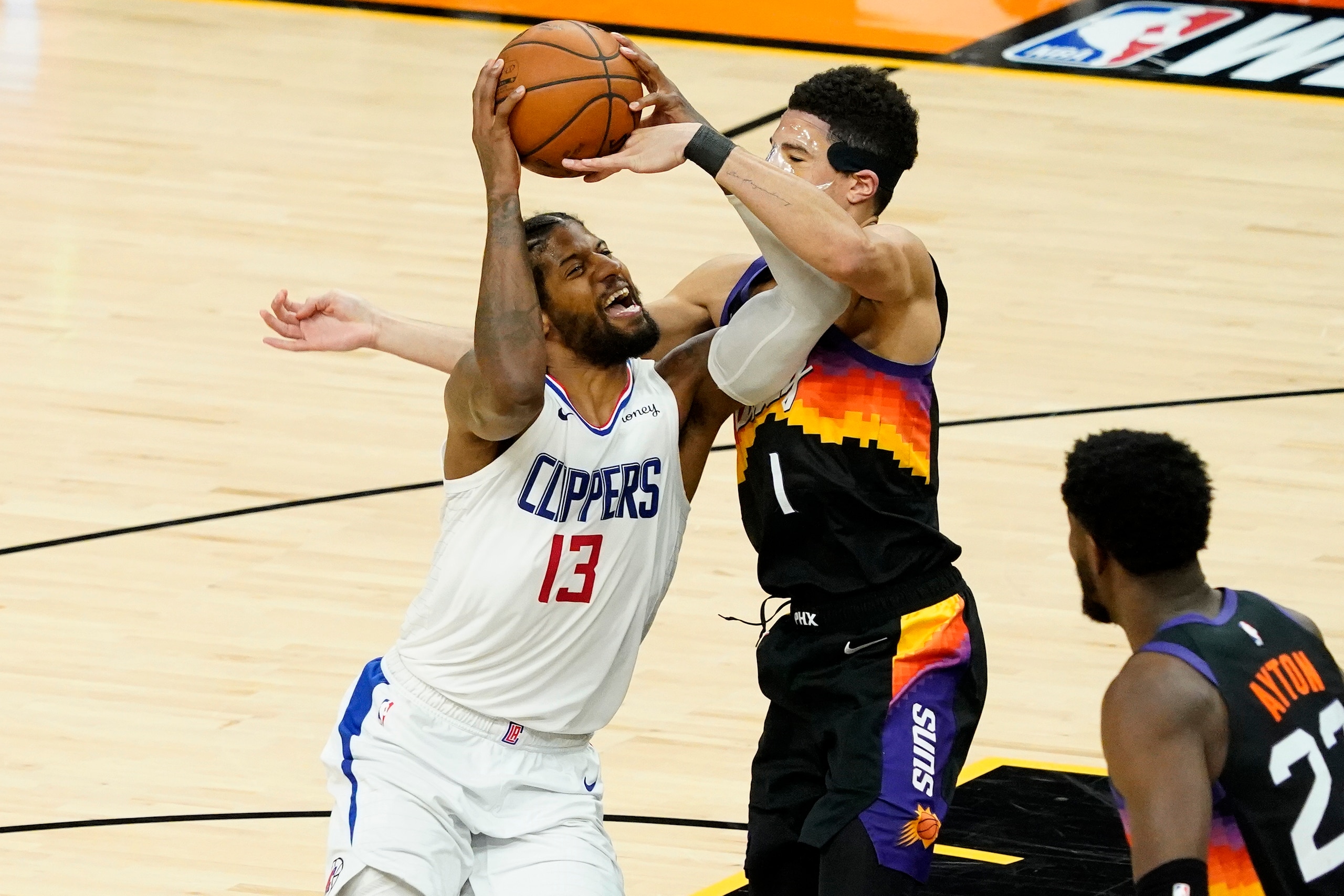 Los Angeles Clippers guard Paul George (13) drives as Phoenix Suns guard Devin Booker (1) defends during the second half of game 5 of the NBA basketball Western Conference Finals, Monday, June 28, 2021, in Phoenix. (AP Photo/Matt York)