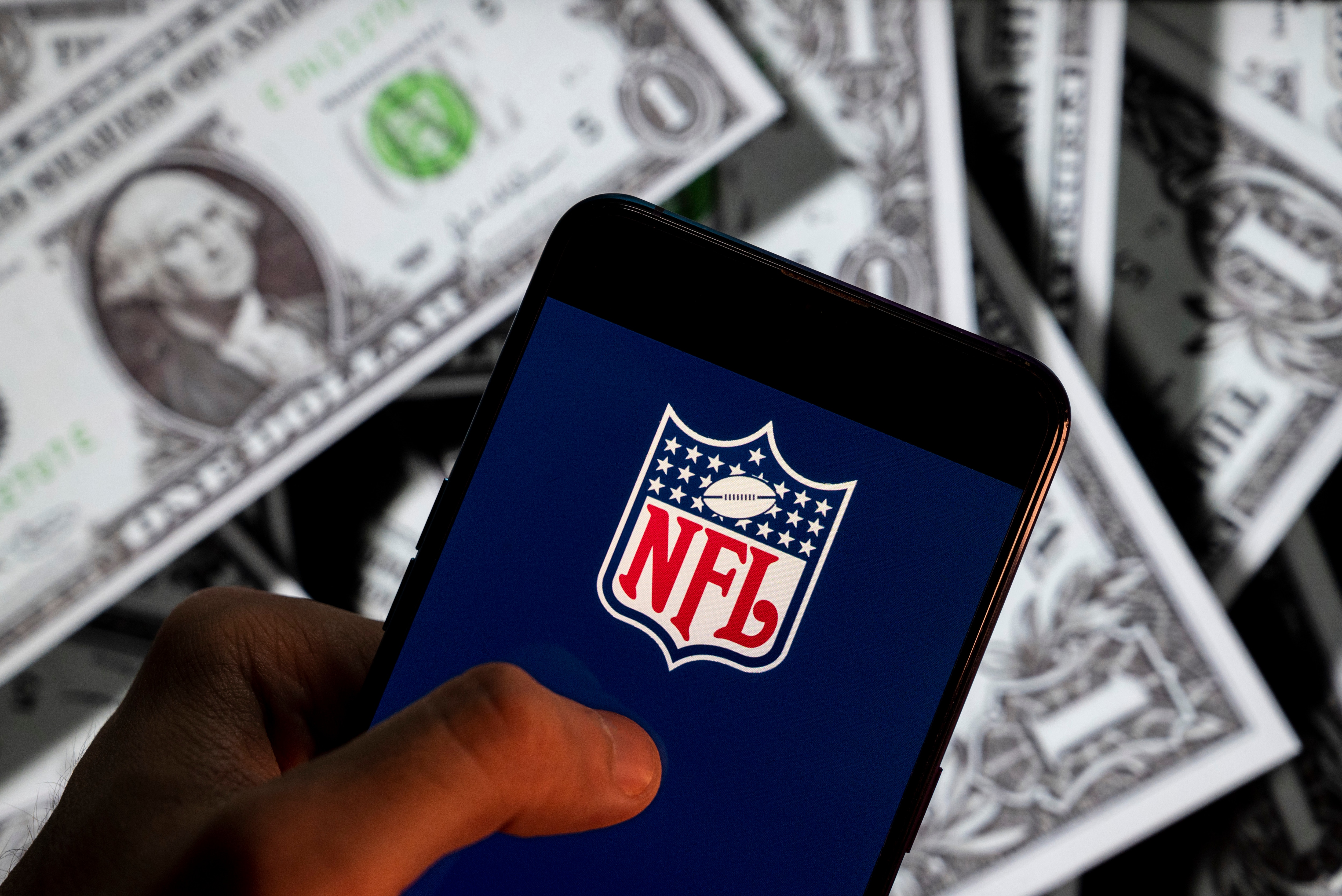 CHINA - 2021/04/23: In this photo illustration the American football league, The National Football League (NFL) logo seen displayed on a smartphone with USD (United States dollar) currency in the background. (Photo Illustration by Budrul Chukrut/SOPA Images/LightRocket via Getty Images)