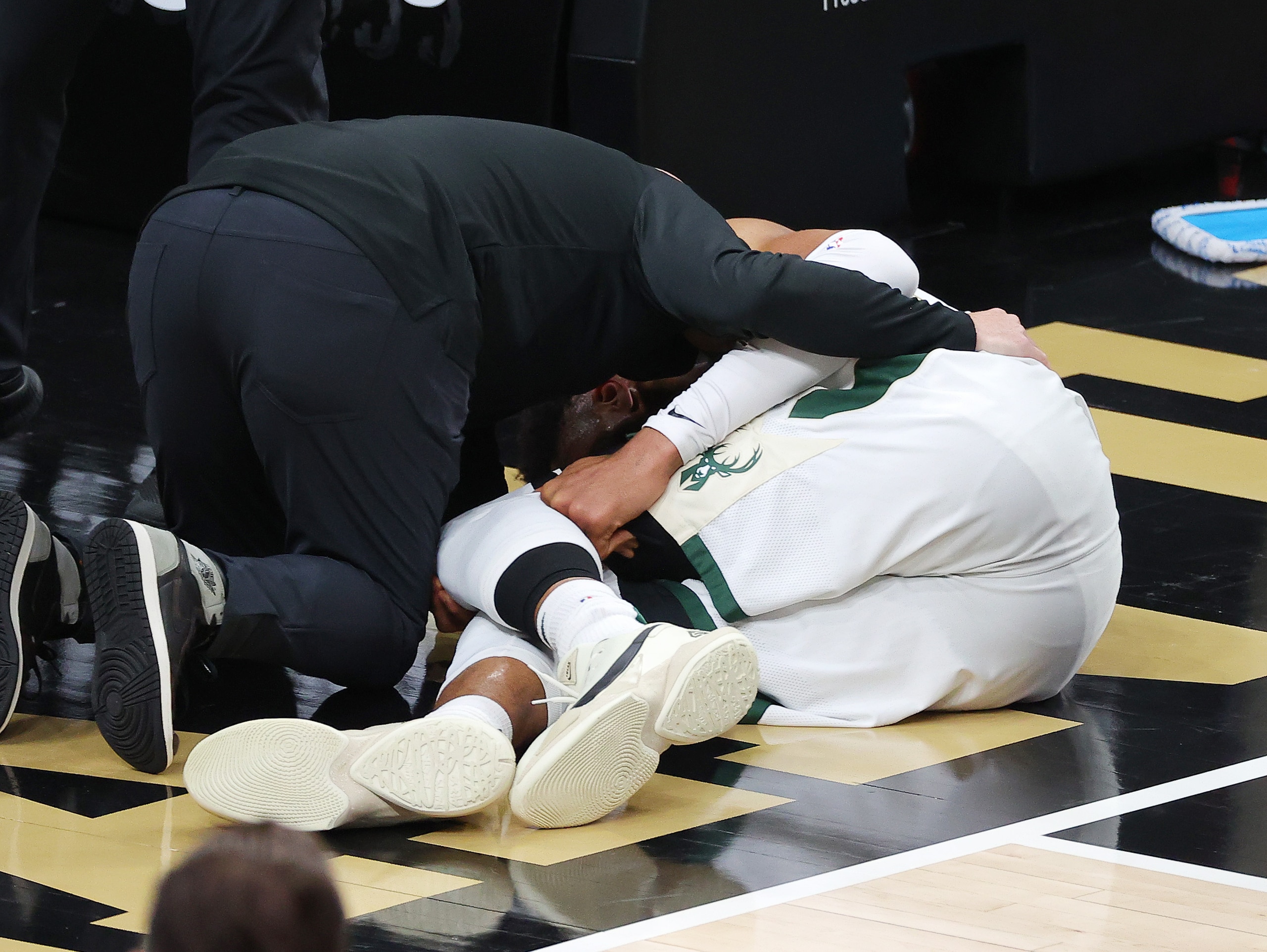 ATLANTA, GEORGIA - JUNE 29: Giannis Antetokounmpo #34 of the Milwaukee Bucks is helped by a trainer after being injured on a play against the Atlanta Hawks during the second half in Game Four of the Eastern Conference Finals at State Farm Arena on June 29, 2021 in Atlanta, Georgia. NOTE TO USER: User expressly acknowledges and agrees that, by downloading and or using this photograph, User is consenting to the terms and conditions of the Getty Images License Agreement. (Photo by Kevin C. Cox/Getty Images)