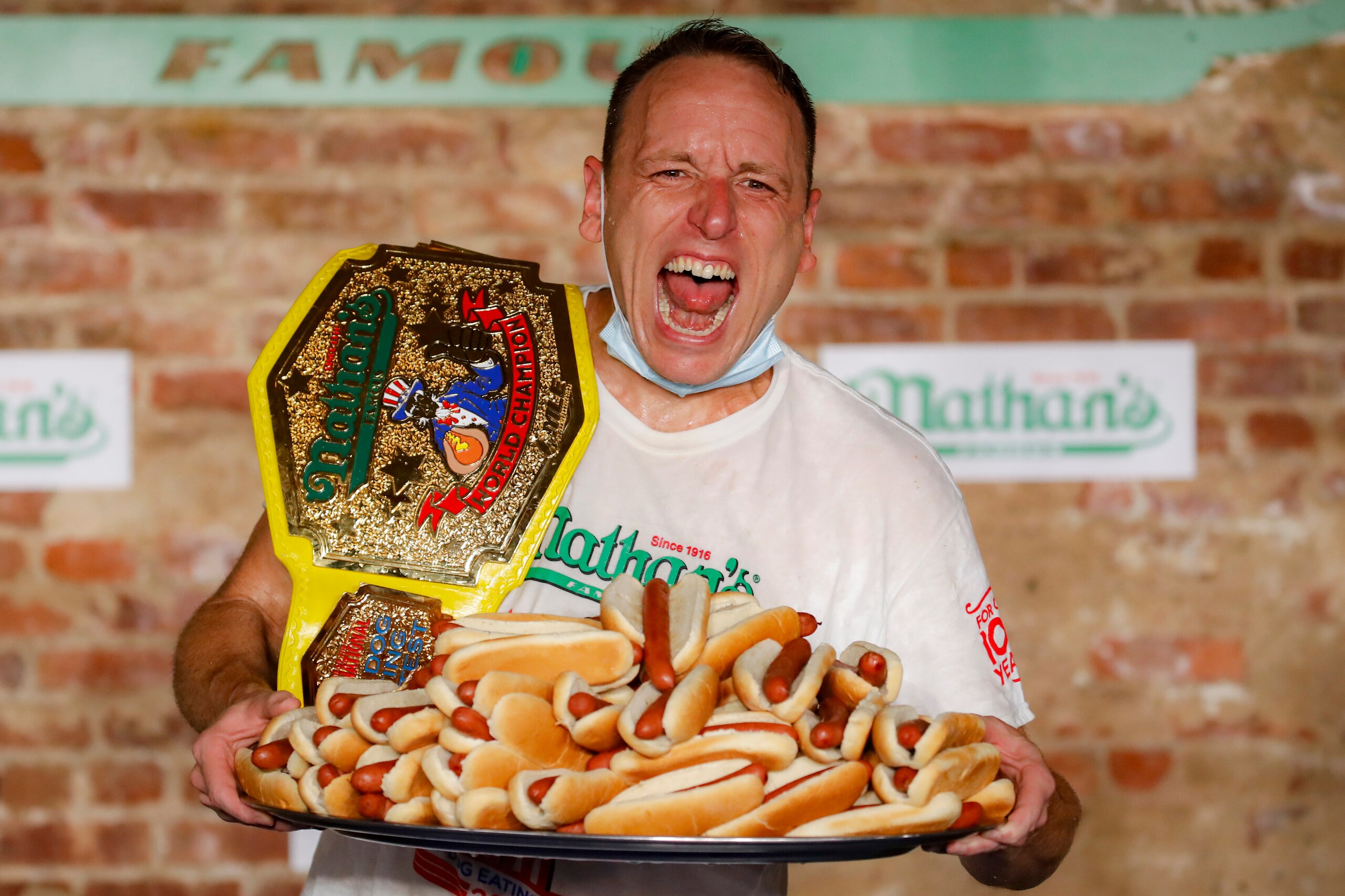 Competitive eater Joey Chestnut celebrates after setting a new world record with 75 hot dogs to win the men's division of the Nathan's Famous July Fourth hot dog eating contest, Saturday, July 4, 2020, in the Brooklyn borough of New York. (AP Photo/John Minchillo)