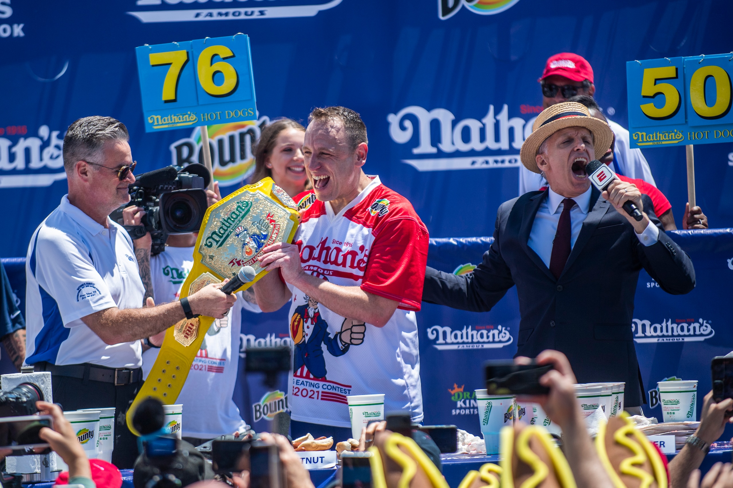 Joey Chestnut, center, reacts after winning the Nathan's Famous Fourth of July International Hot Dog-Eating Contest in Coney Island's Maimonides Park on Sunday, July 4, 2021, in New York. (AP Photo/Brittainy Newman)