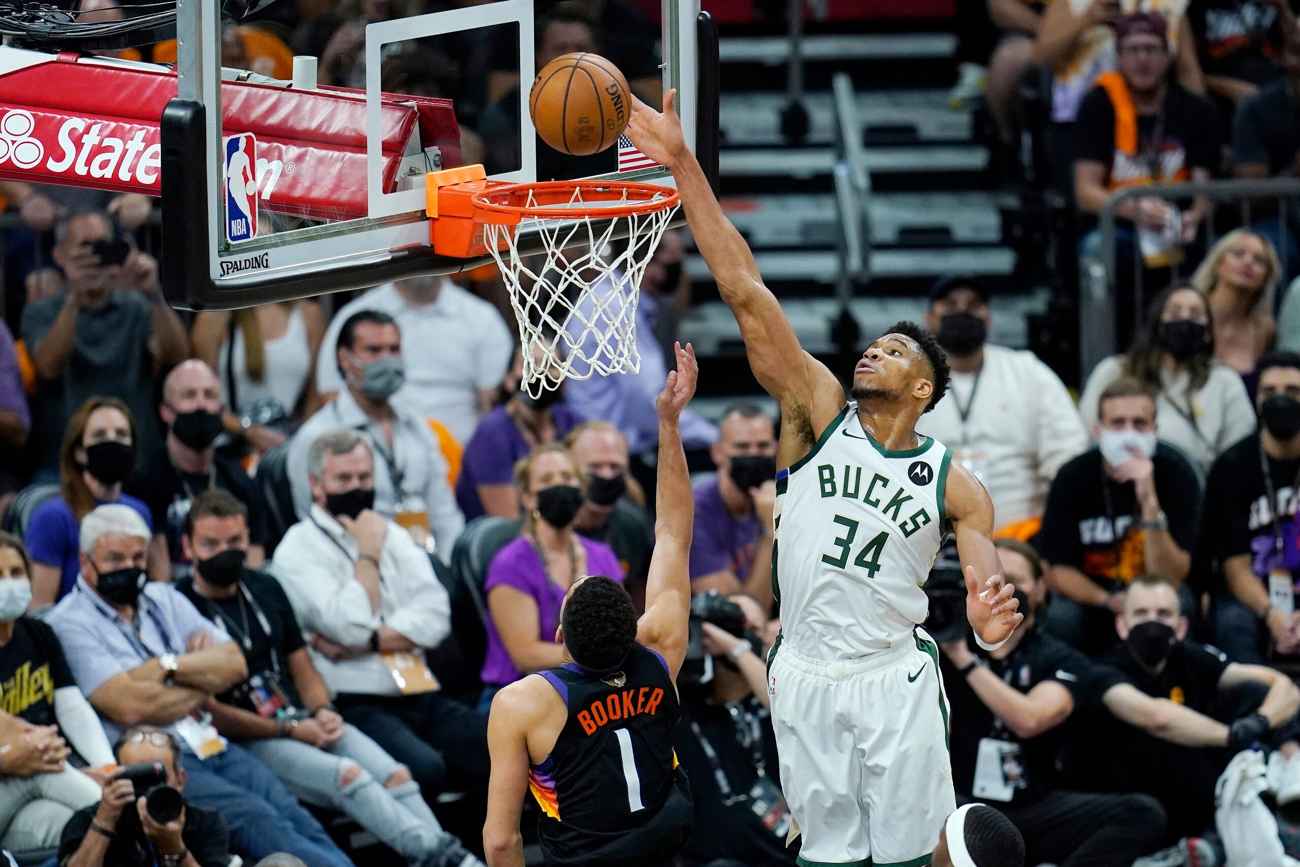 Phoenix Suns guard Devin Booker (1) scores as Milwaukee Bucks forward Giannis Antetokounmpo (34) is called for goaltending during the first half of Game 1 of basketball's NBA Finals, Tuesday, July 6, 2021, in Phoenix. (AP Photo/Ross D. Franklin)
