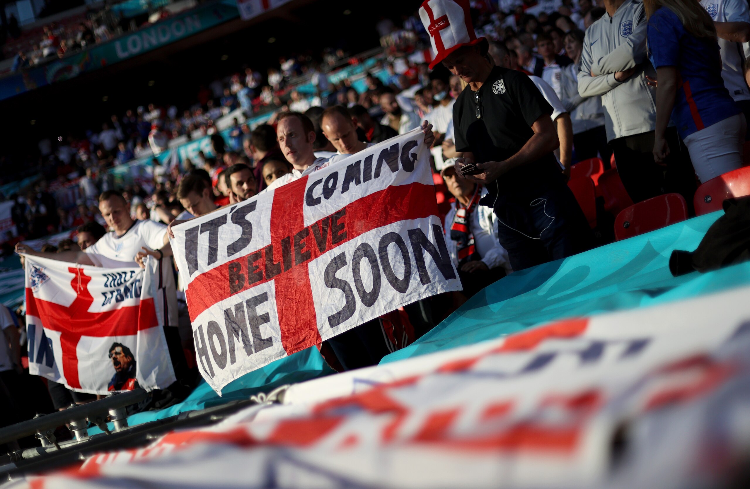 LONDON, ENGLAND - JULY 07: A fan of England holds a flag with the words "It's coming home soon" wrote on prior to the UEFA Euro 2020 Championship Semi-final match between England and Denmark at Wembley Stadium on July 07, 2021 in London, England. (Photo by Carl Recine - Pool/Getty Images)