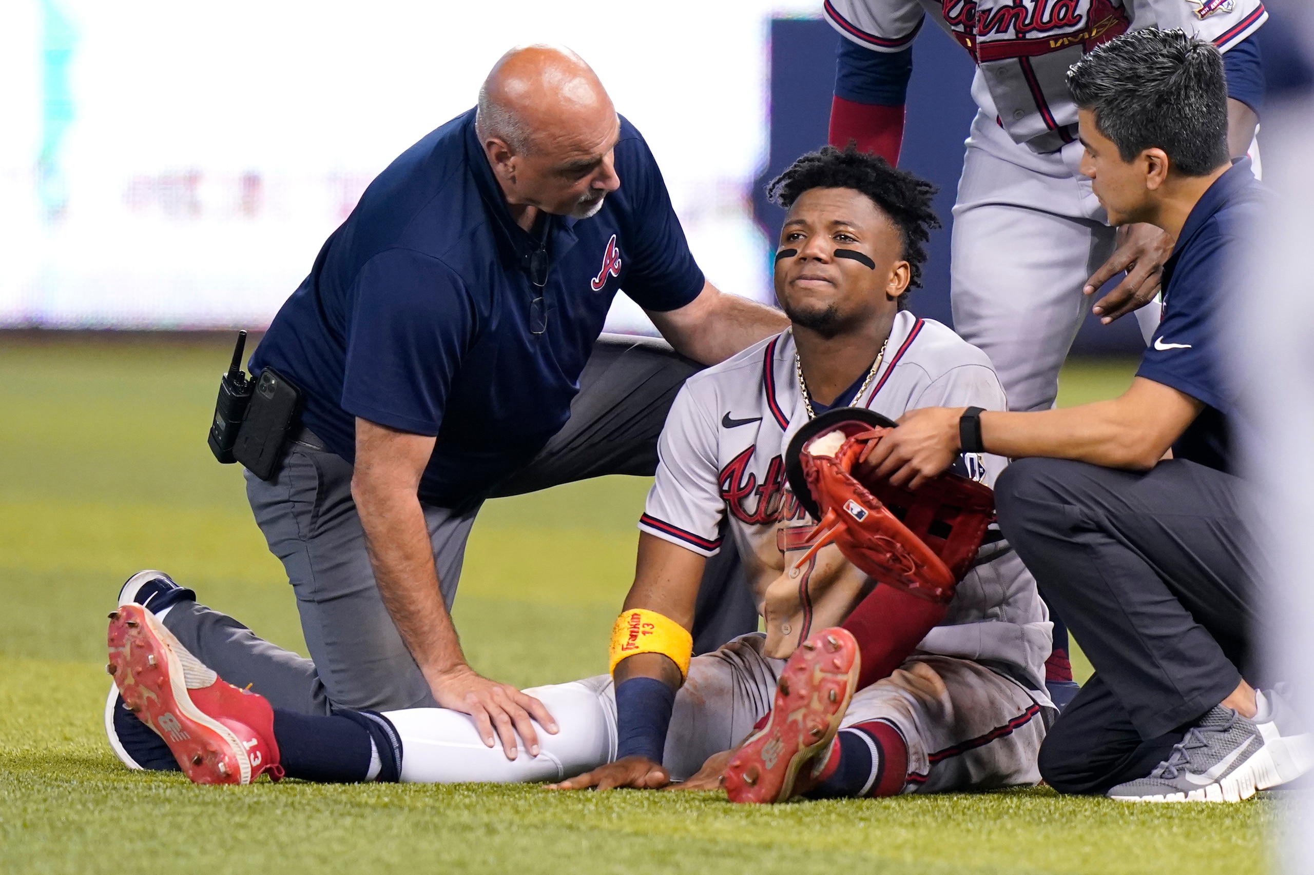 Atlanta Braves right fielder Ronald Acuna Jr., sits injured on the field after trying to make a catch on an inside the park home run hit by Miami Marlins' Jazz Chisholm Jr. during the fifth inning of a baseball game, Saturday, July 10, 2021, in Miami. (AP Photo/Lynne Sladky)