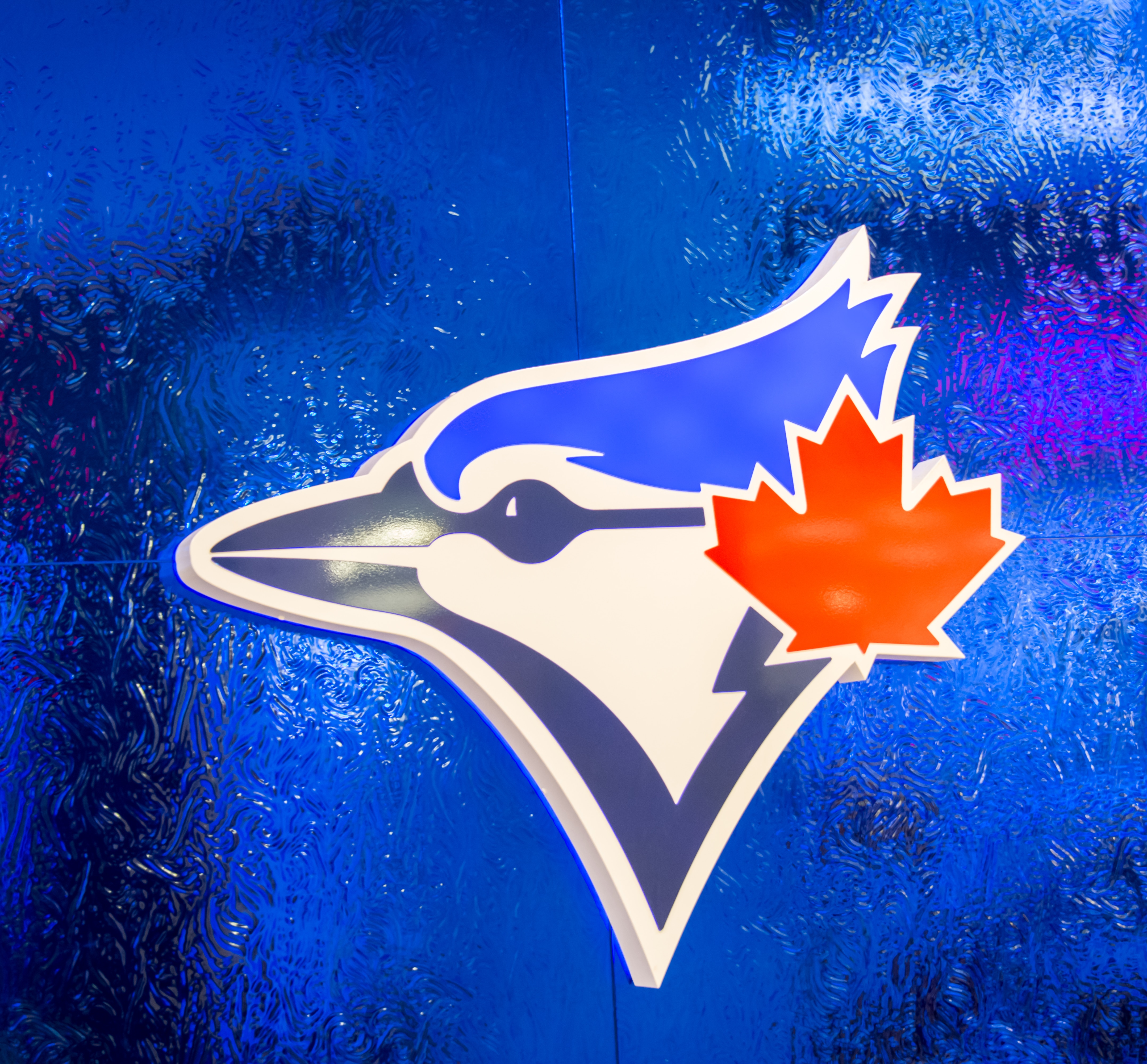 TORONTO, ONTARIO, CANADA - 2015/05/13: Square Logo of the Toronto Blue Jays baseball team on a blue frosted glass. The logo features the head of the 'Blue Jay' bird and the Canadian maple leaf in red. 

The Toronto Blue Jays are a Canadian professional baseball team based in Toronto, Ontario. The Blue Jays are a member of the East division of the American League in Major League Baseball. (Photo by Roberto Machado Noa/LightRocket via Getty Images)