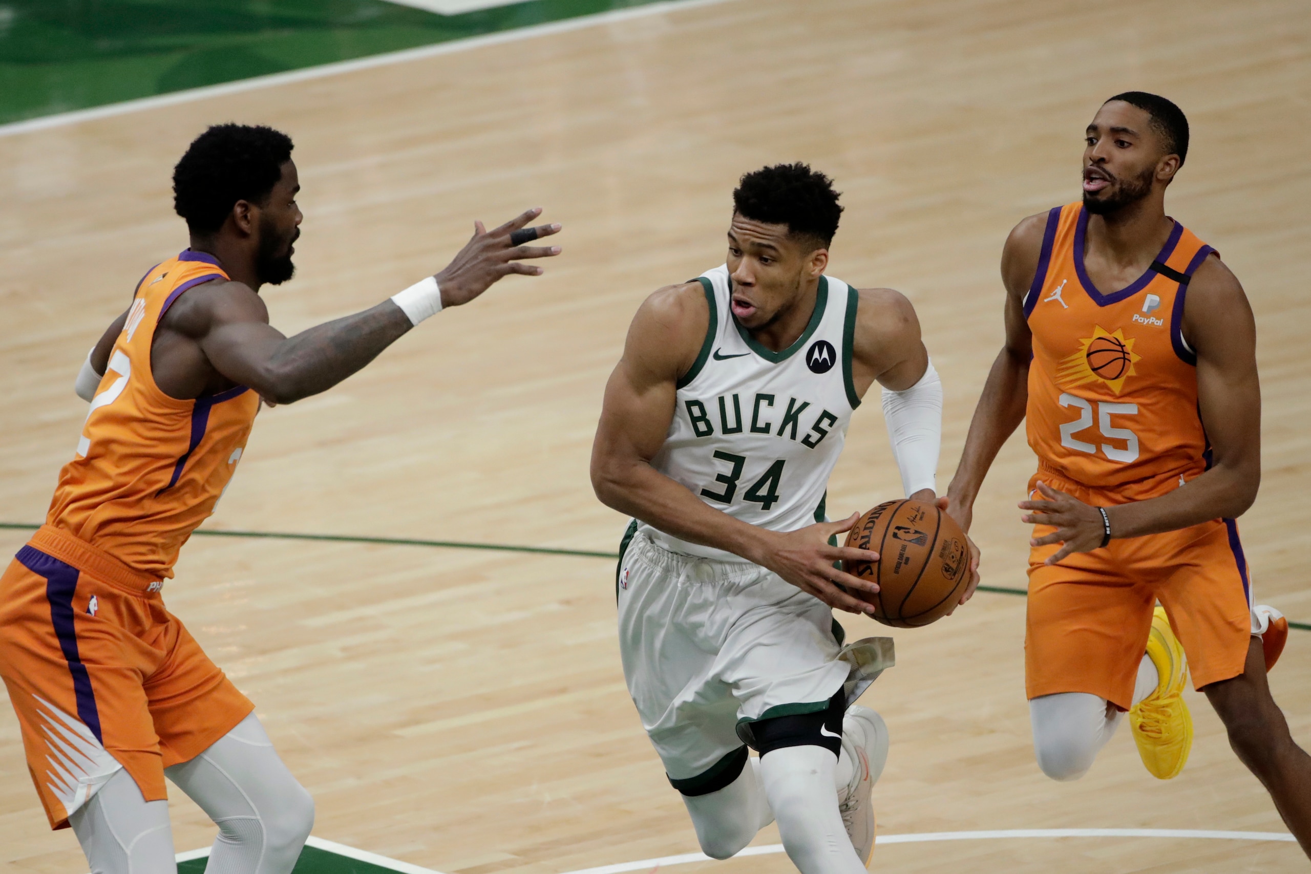 Milwaukee Bucks forward Giannis Antetokounmpo (34) drives to the basket between Phoenix Suns center Deandre Ayton, left, and forward Mikal Bridges (25) during the second half of Game 4 of basketball's NBA Finals Wednesday, July 14, 2021, in Milwaukee. (AP Photo/Aaron Gash)