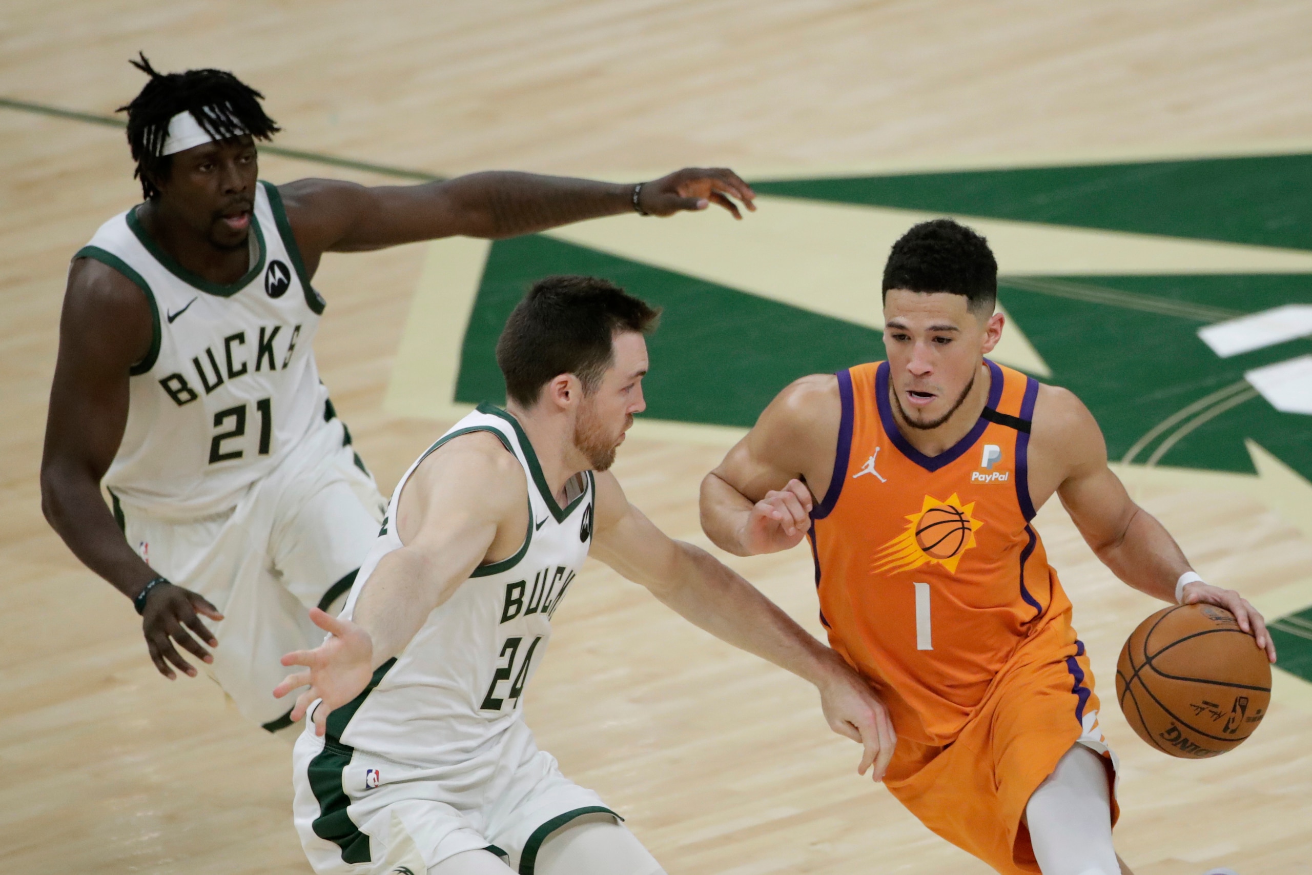 Phoenix Suns guard Devin Booker (1) drives past Milwaukee Bucks guard Pat Connaughton (24) and guard Jrue Holiday (21) during the first half of Game 4 of basketball's NBA Finals Wednesday, July 14, 2021, in Milwaukee. (AP Photo/Aaron Gash)